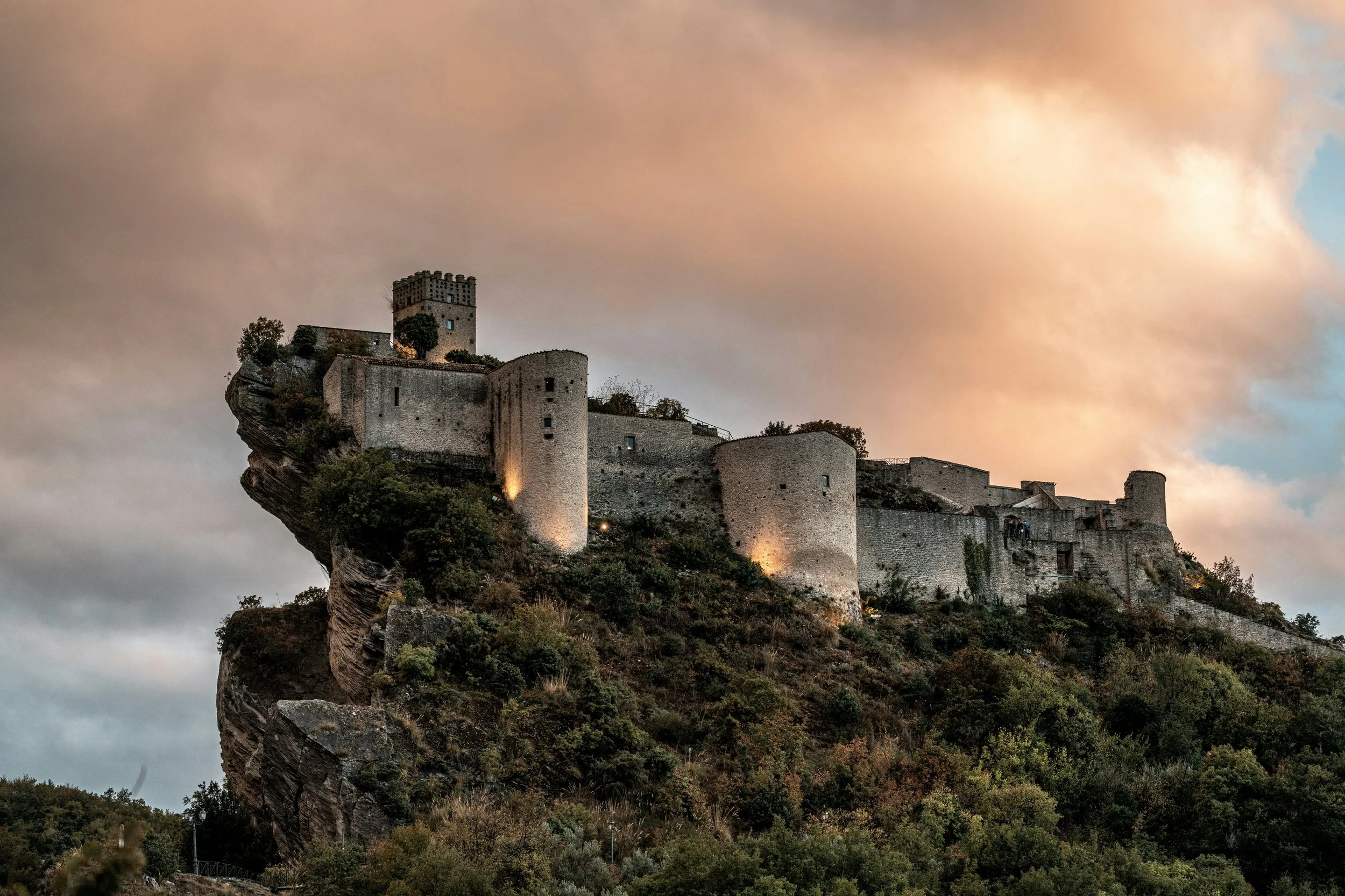 Roccascalegna Castle perched on a rocky ridge beneath a glowing evening sky in Abruzzo.