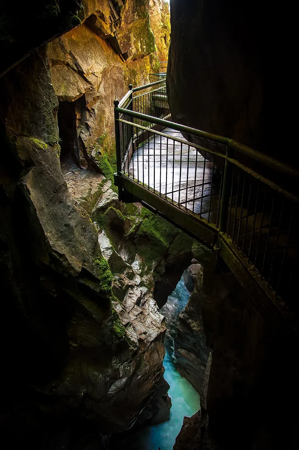 A narrow metal walkway above turquoise water between the rock walls of the Orrido di Bellano.