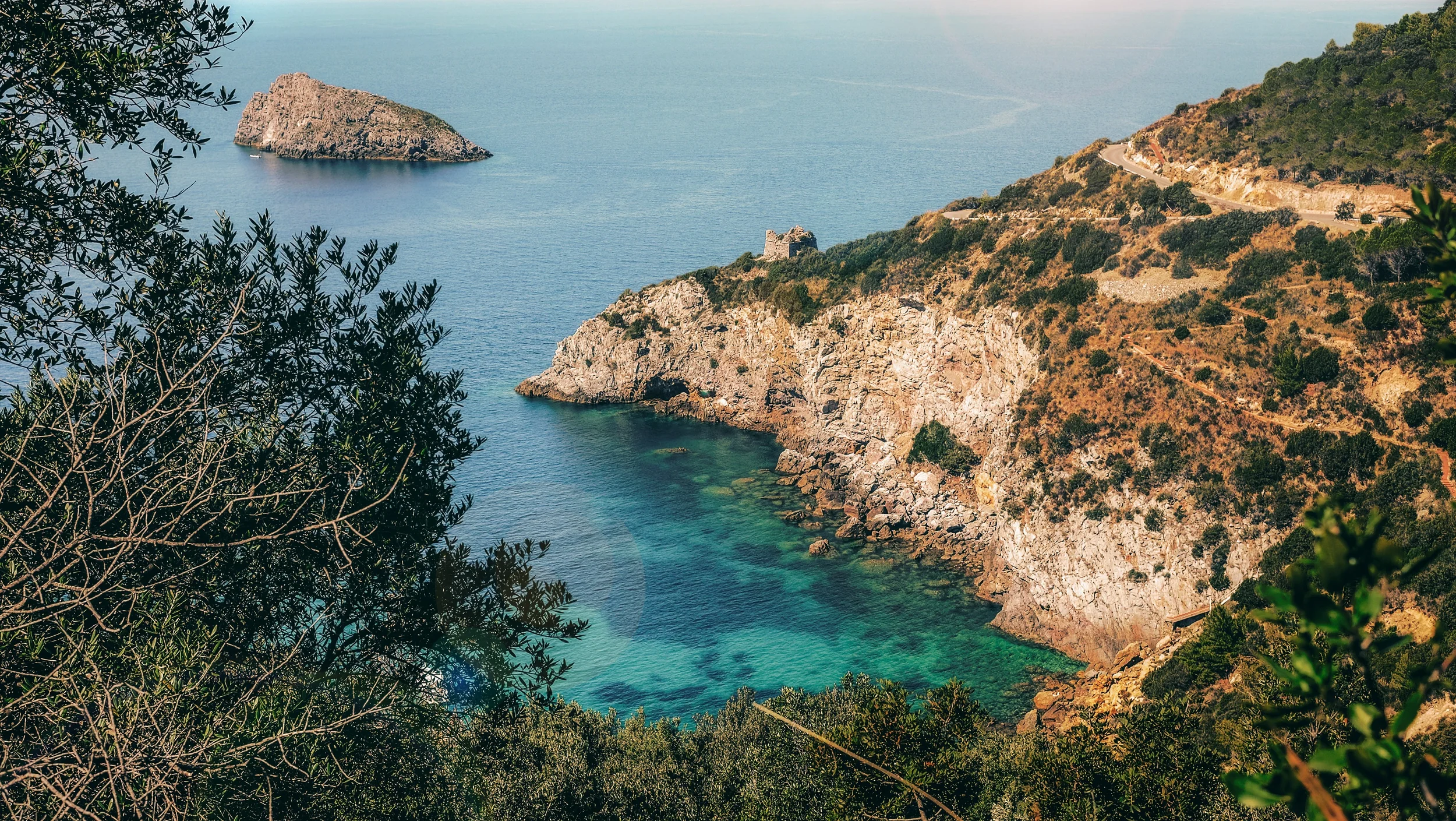 Cala del Gesso on the Monte Argentario coast, with turquoise water, rocky cliffs and a small island off the Tuscan shore