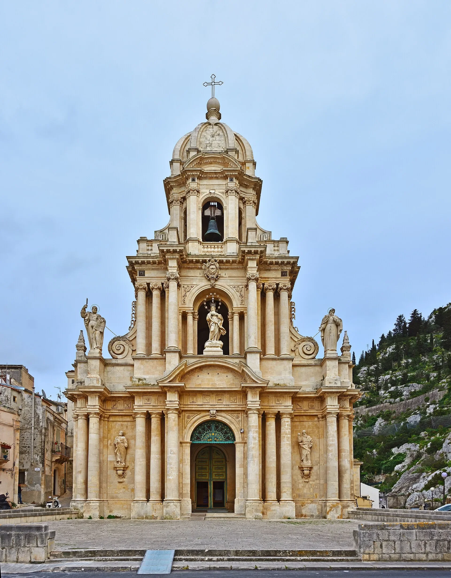 The ornate façade and bell tower of San Bartolomeo church in Scicli, with its entrance steps and rocky hillside