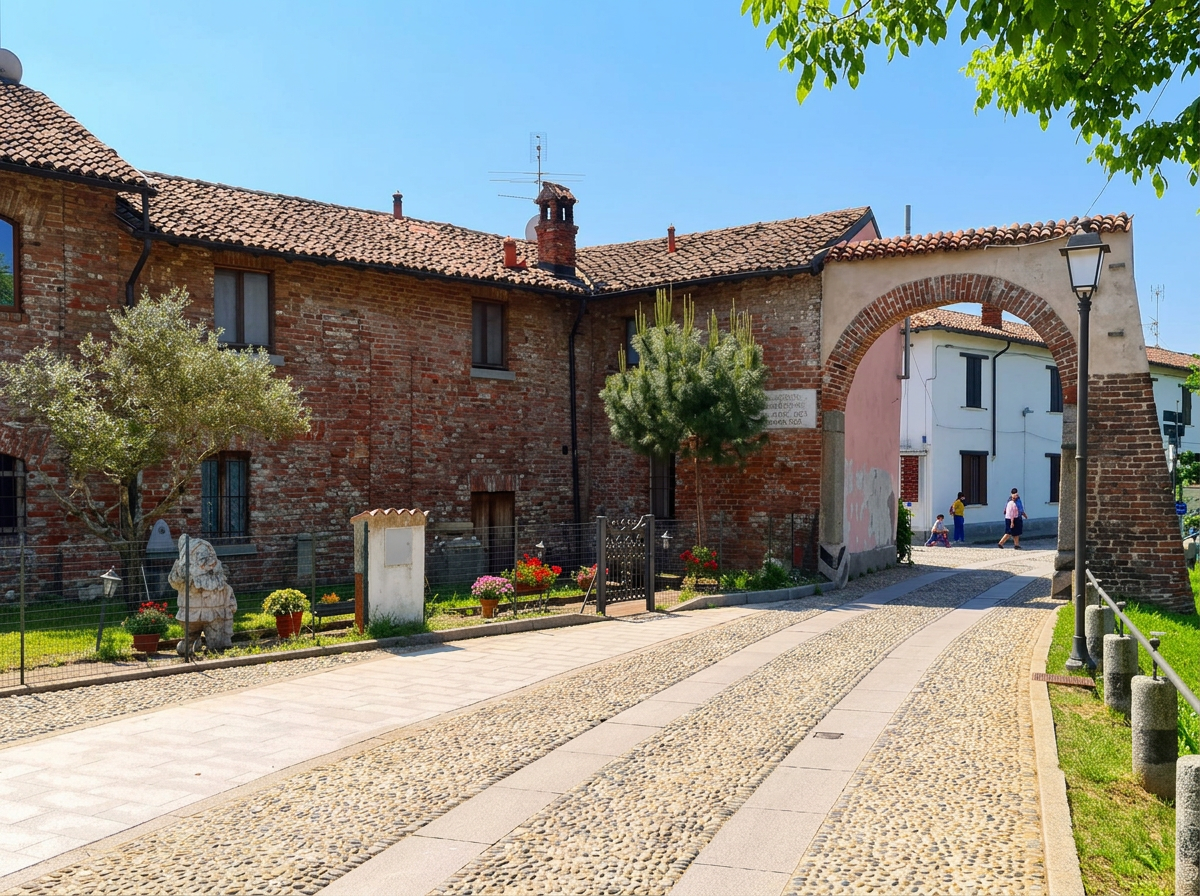 Cobbled street leading through a brick archway in Morimondo, Lombardy.