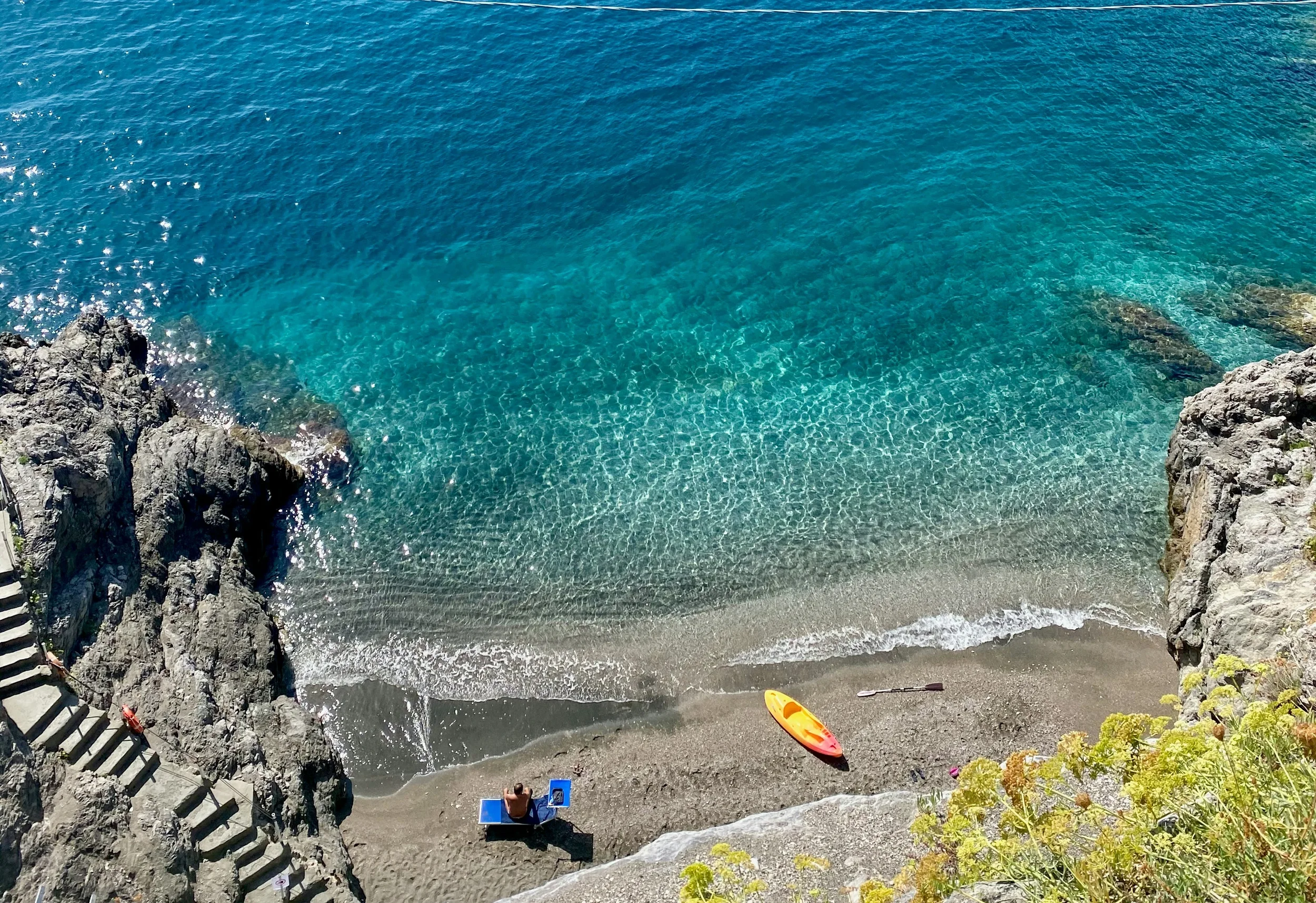 Rocky beach with crystal-clear turquoise water on the Campania coast, Italy
