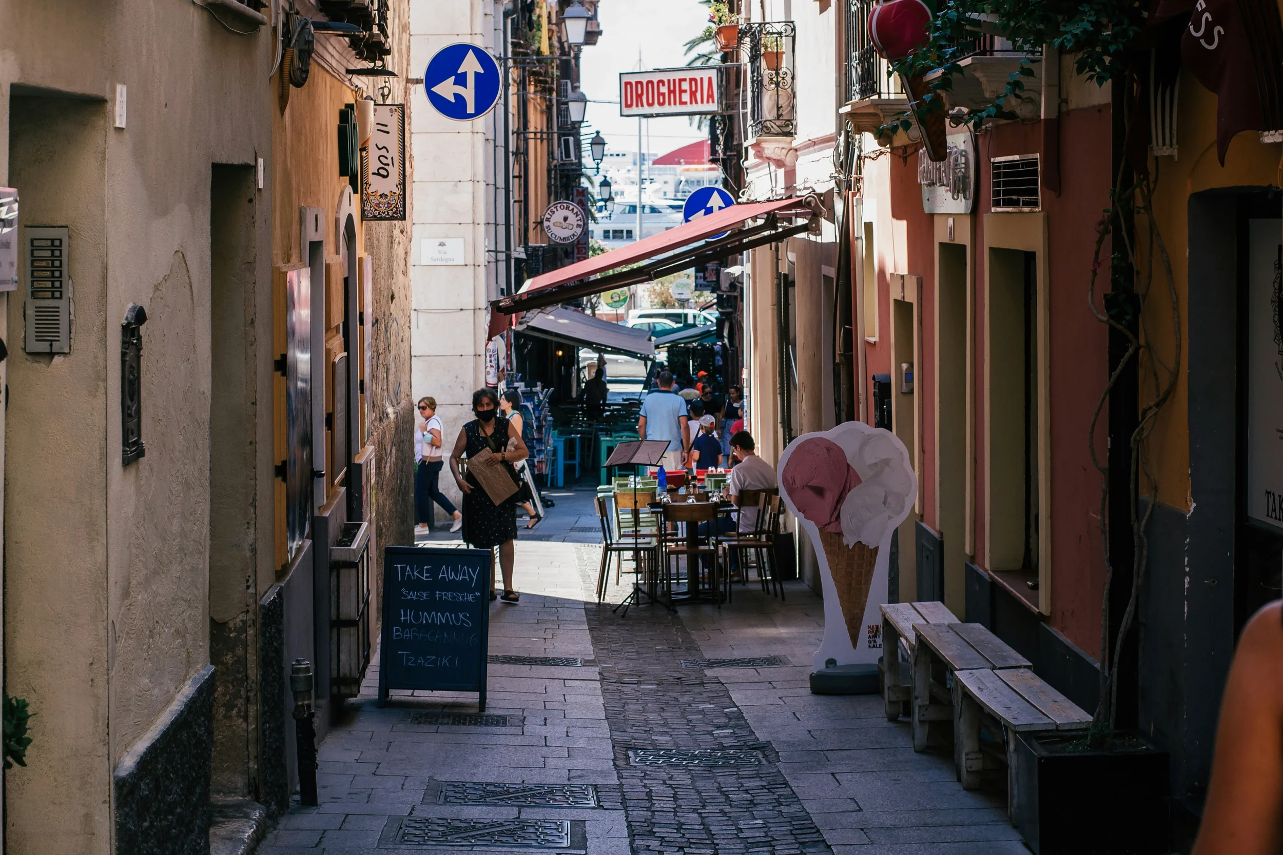 Narrow street in Cagliari’s historic centre with colourful buildings, local restaurants and outdoor terraces.