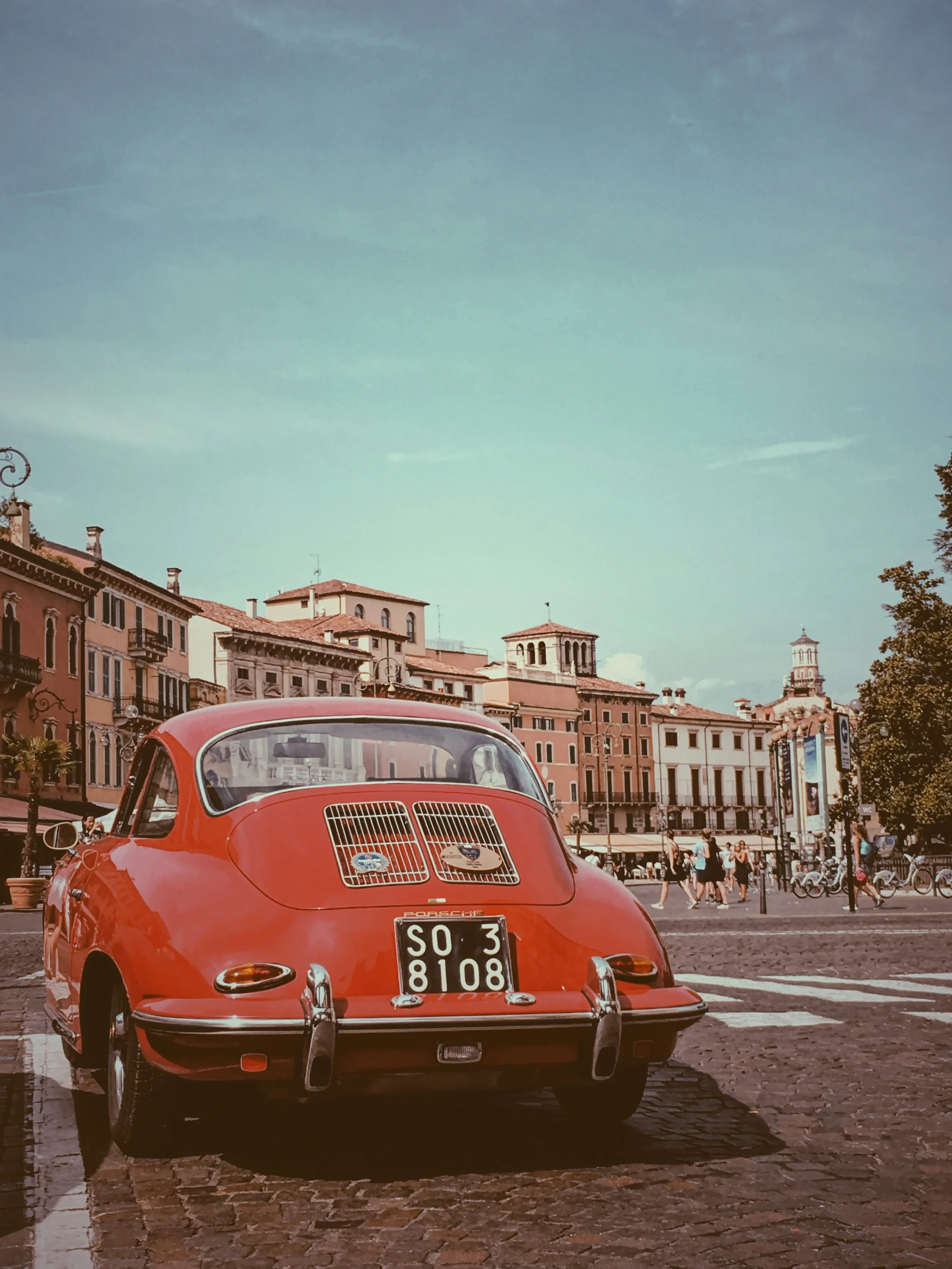 Vintage red car in a historic city square during an Emilia-Romagna road trip