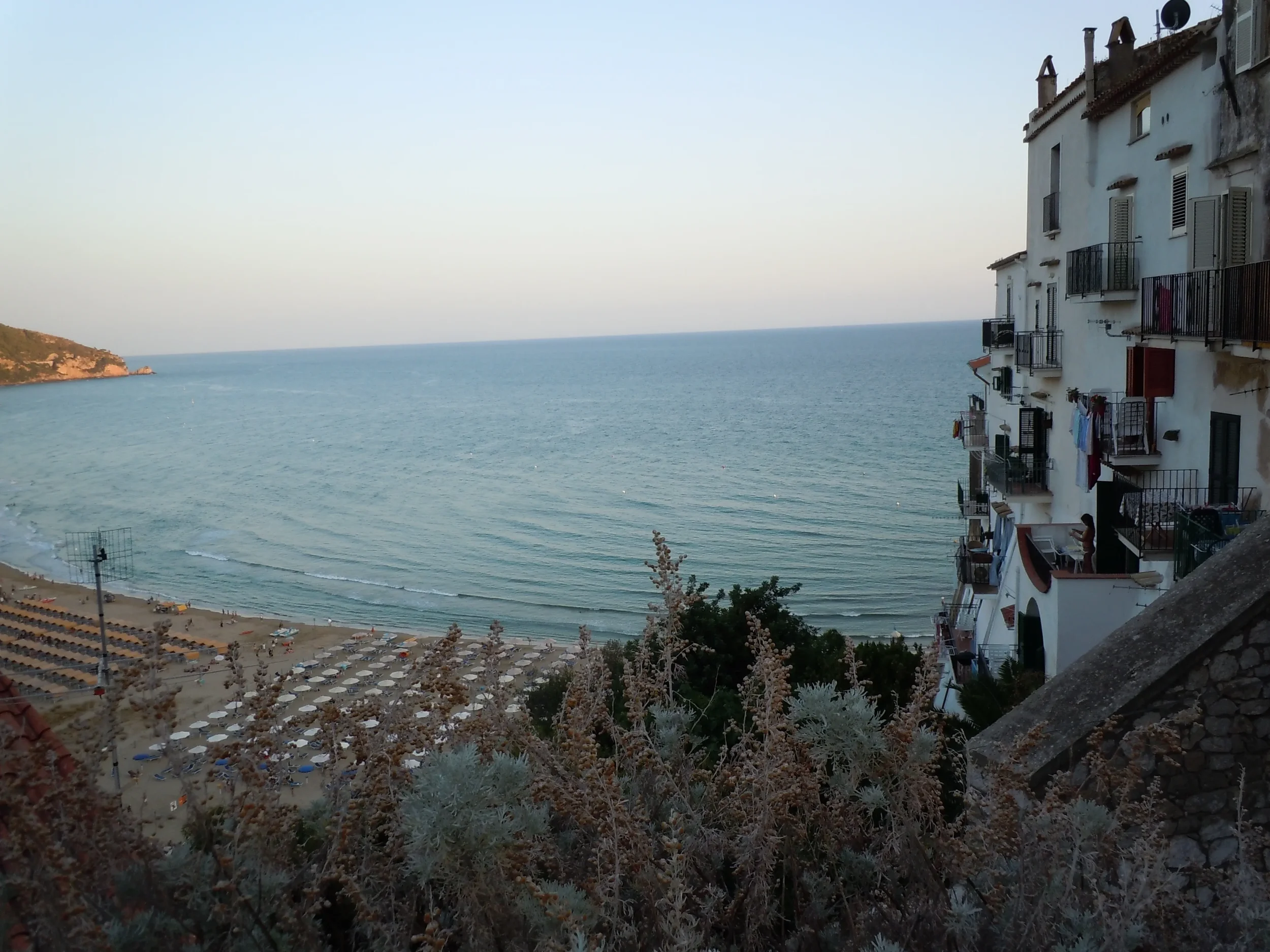 White houses with balconies above Sperlonga’s beach, with rows of parasols and a wide view across the sea.