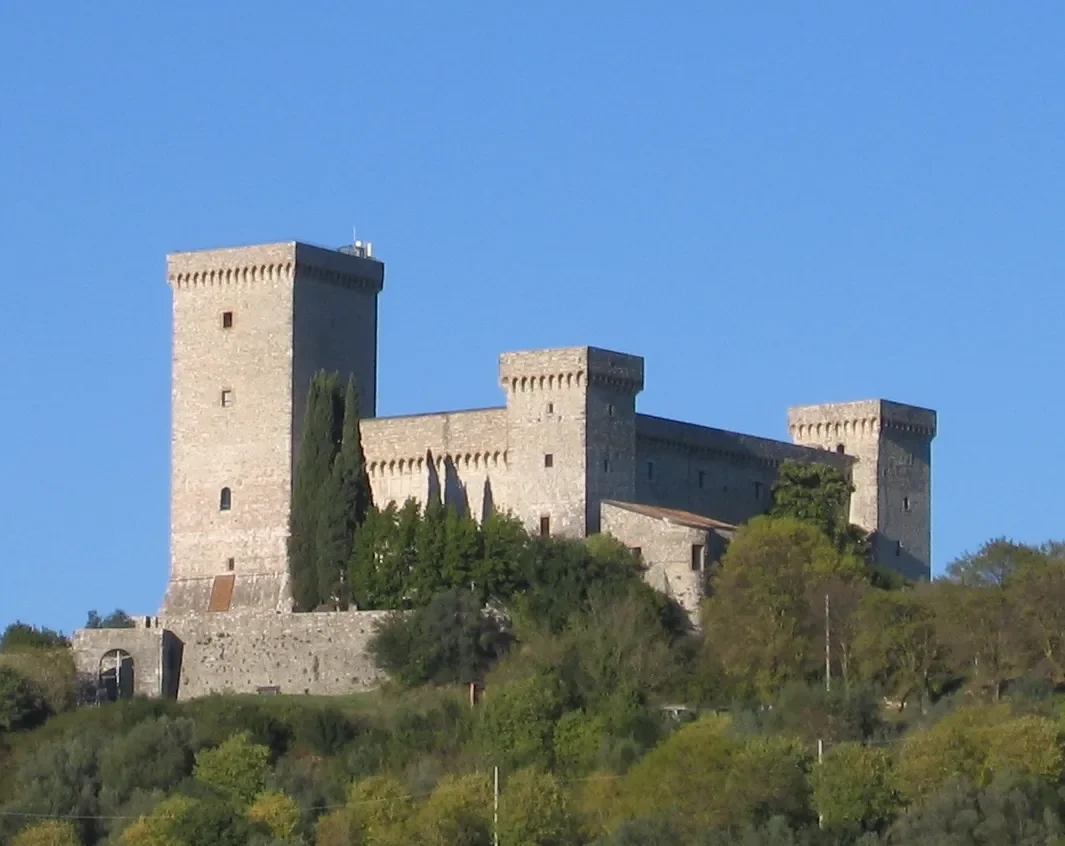 Square towers of the Rocca Albornoz fortress rising above trees on the hill above Narni