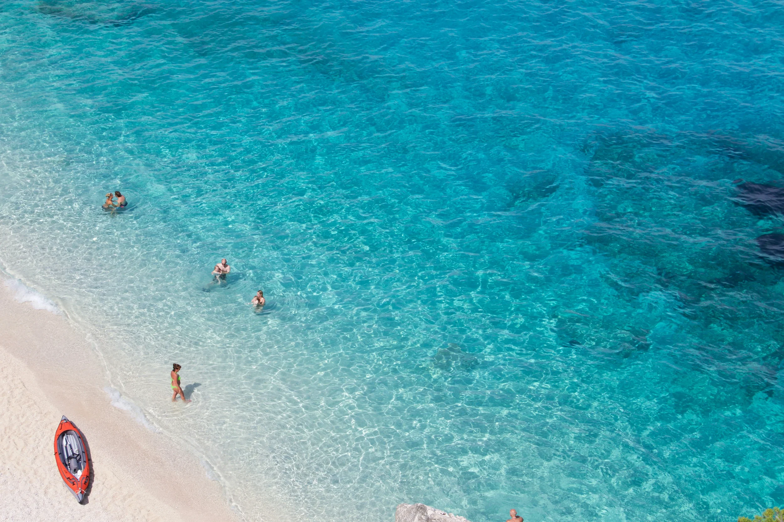 Aerial view of Cala Goloritzè in Sardinia, with turquoise water, white sand, swimmers and a kayak