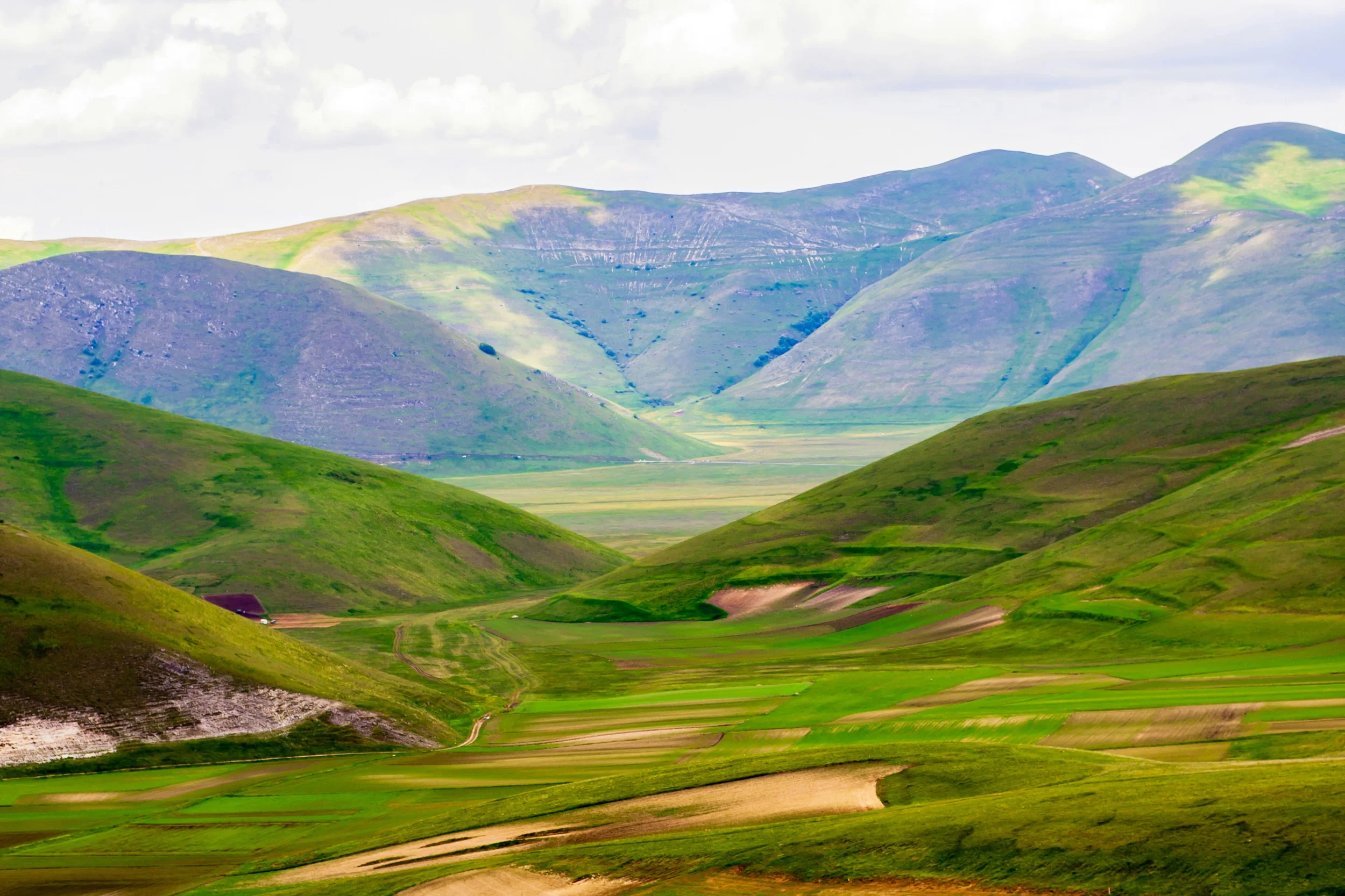 Green mountain slopes and patchwork fields in the high plains around Castelluccio di Norcia