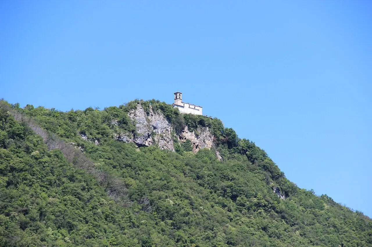 The white Madonna della Ceriola sanctuary above the rocky, wooded summit of Monte Isola.