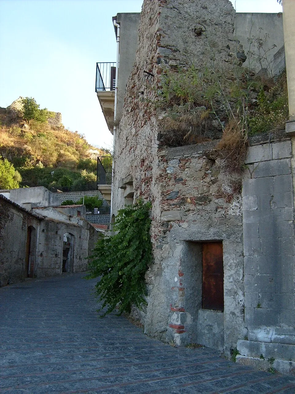 Weathered stone walls and a small wooden door at Savoca’s former prison, beside a cobbled lane