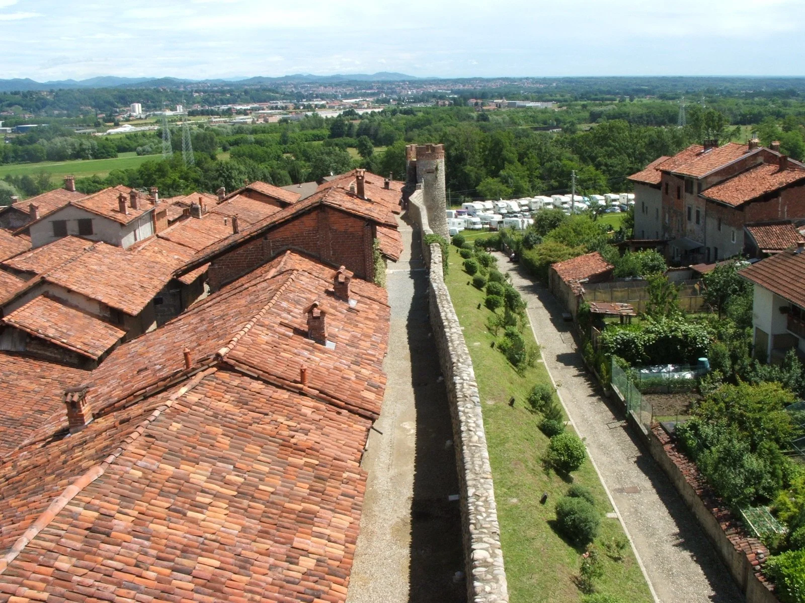 Terracotta rooftops and a round defensive tower along the walls of Ricetto di Candelo