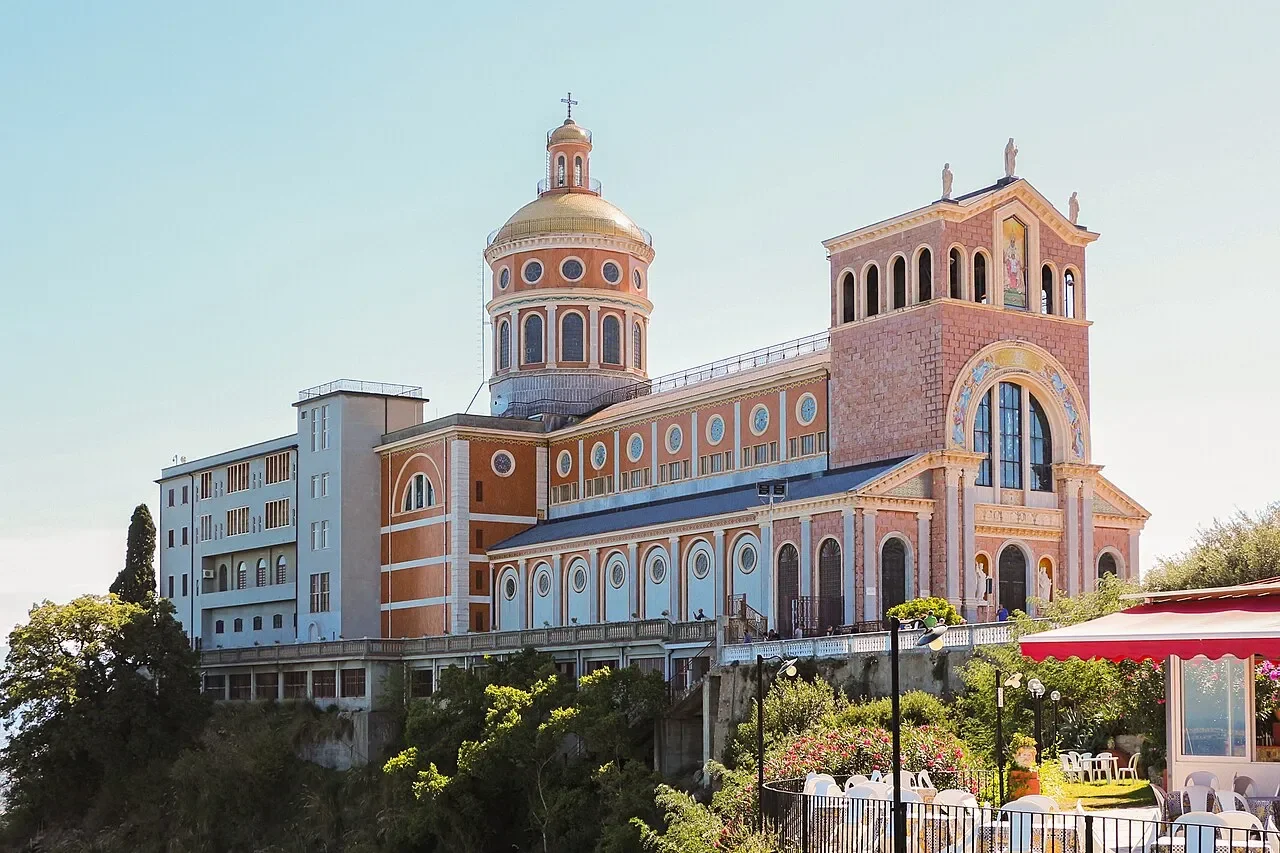 The Sanctuary of the Black Madonna in Tindari, with its golden dome and colourful facade above the hillside