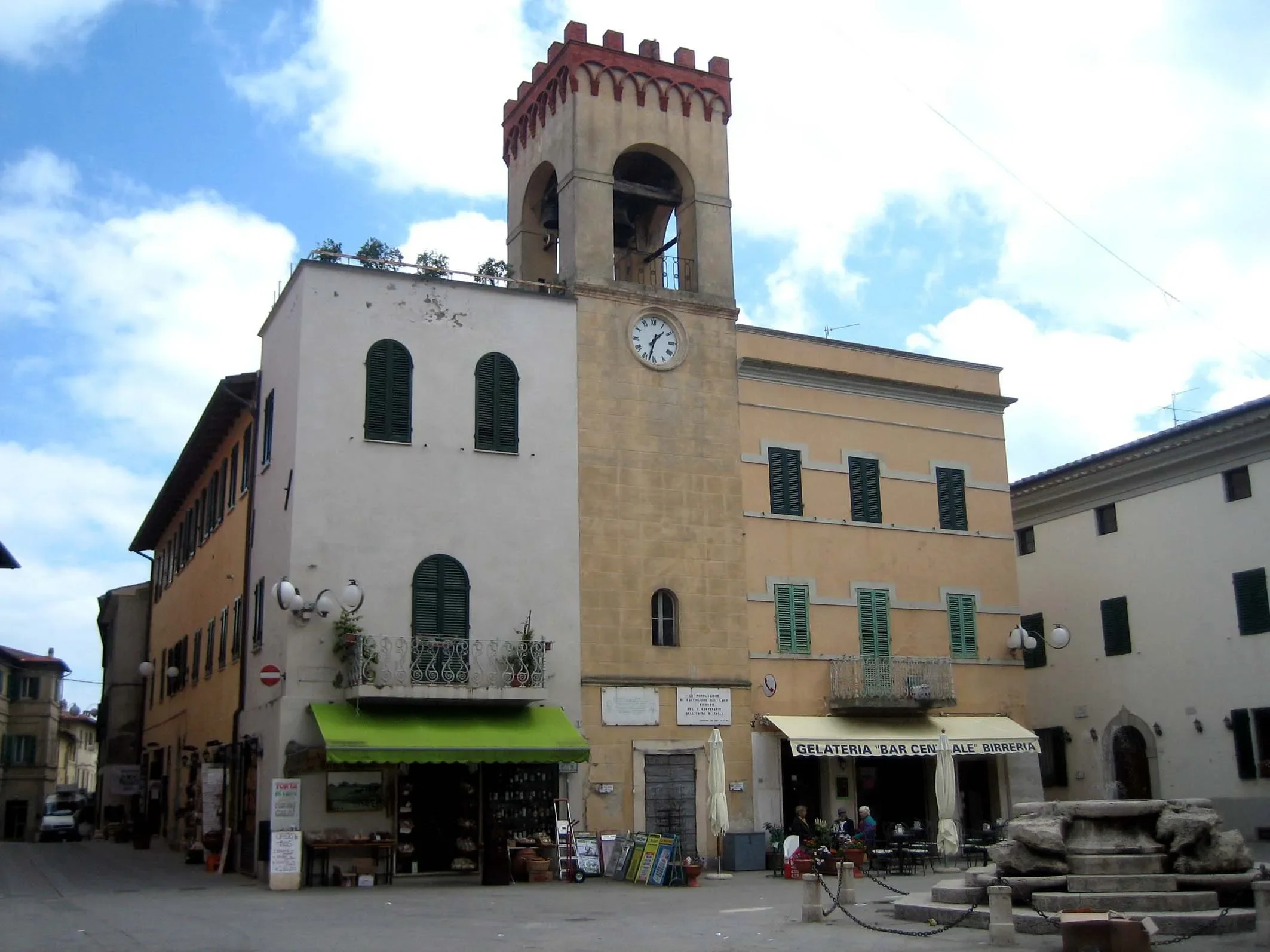 Clock tower, pastel façades and stone fountain in Piazza Mazzini, Castiglione del Lago
