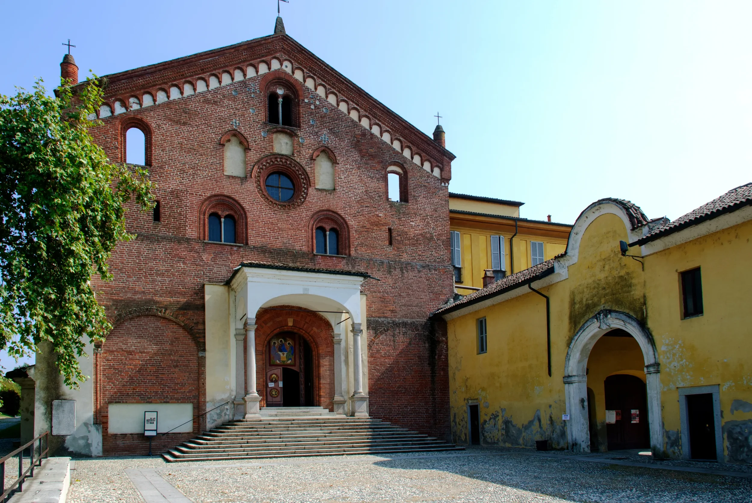 Brick façade and entrance steps of Morimondo Abbey beside the monastery gateway.