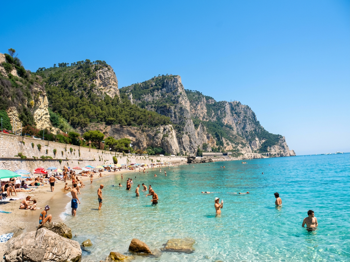 Swimmers in turquoise water beneath limestone cliffs on the coast near Noli, Liguria
