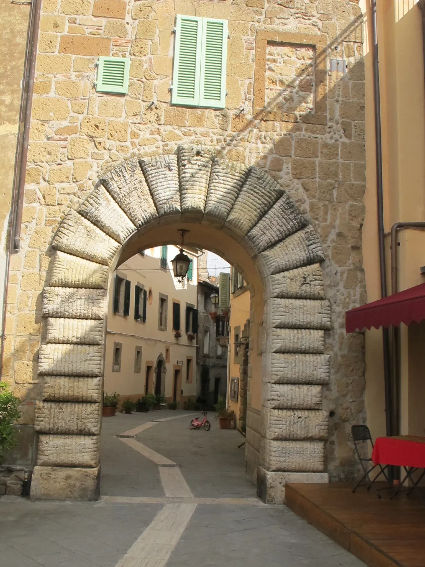 Rusticated stone arch of Porta di Sopra opening onto a narrow street in Sorano’s old town.