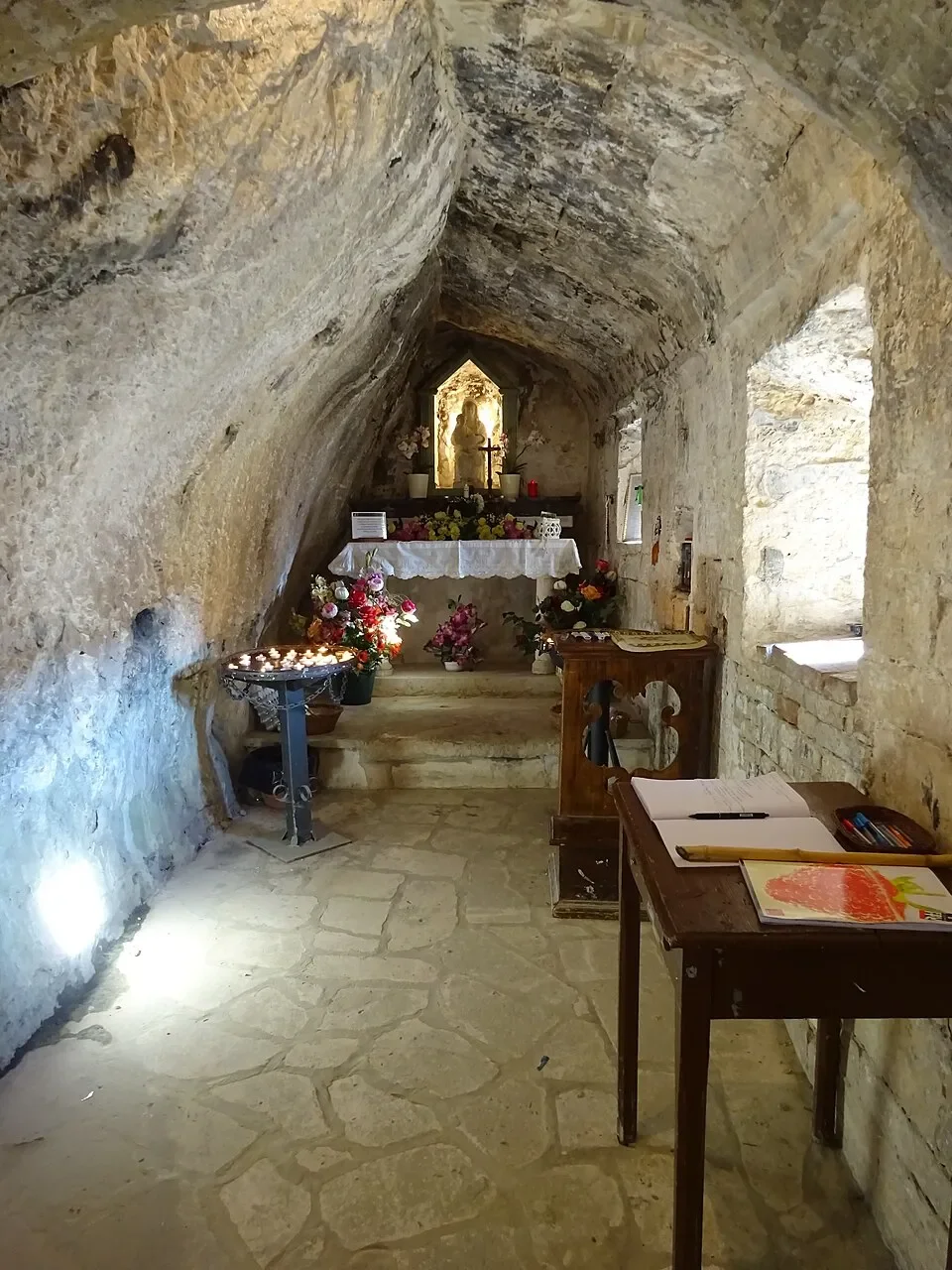 The small altar and flowers inside Santa Maria Infra Saxa, beneath the natural rock ceiling