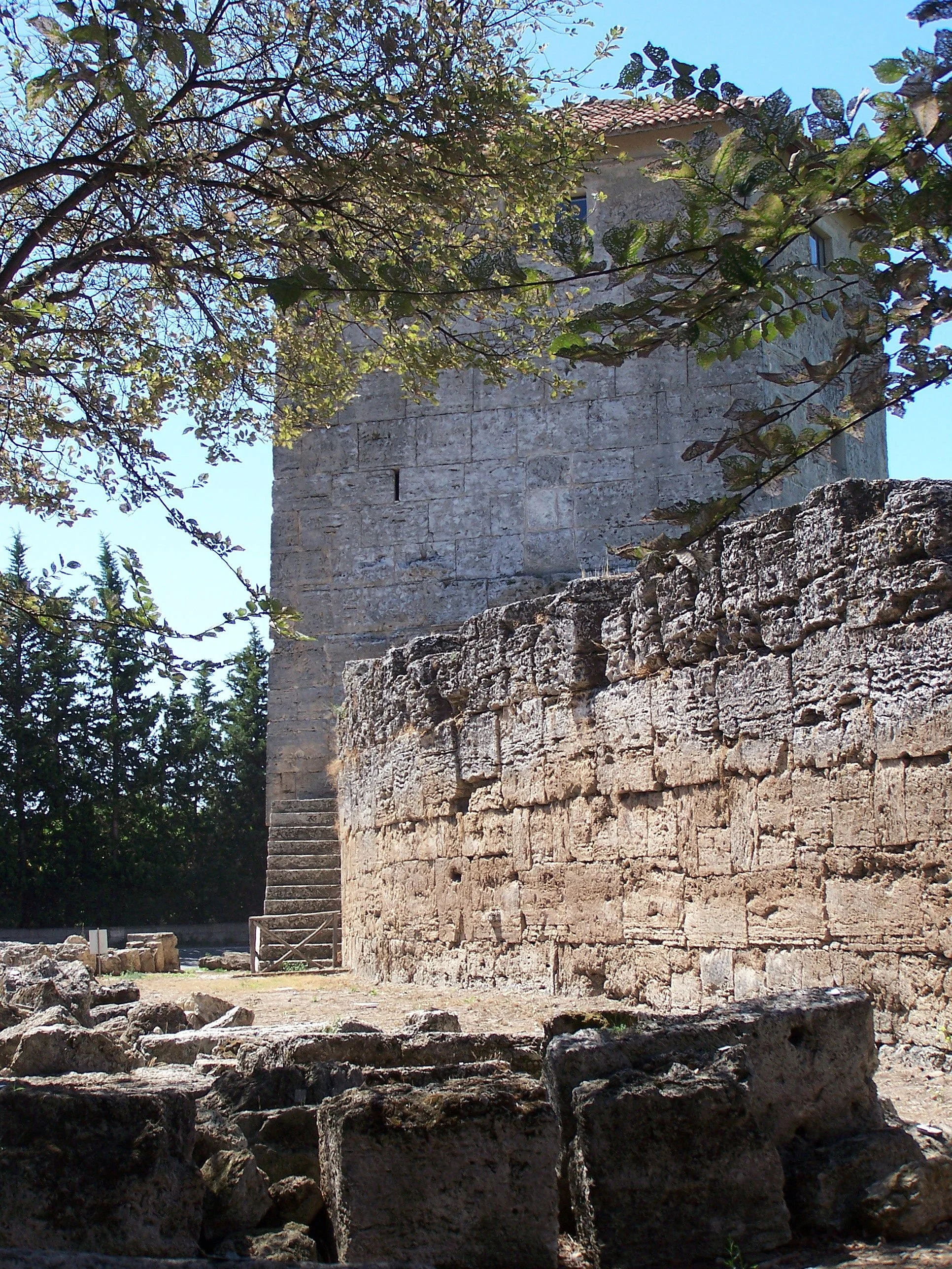Stone building and ancient masonry framed by trees in the Capaccio Paestum area.