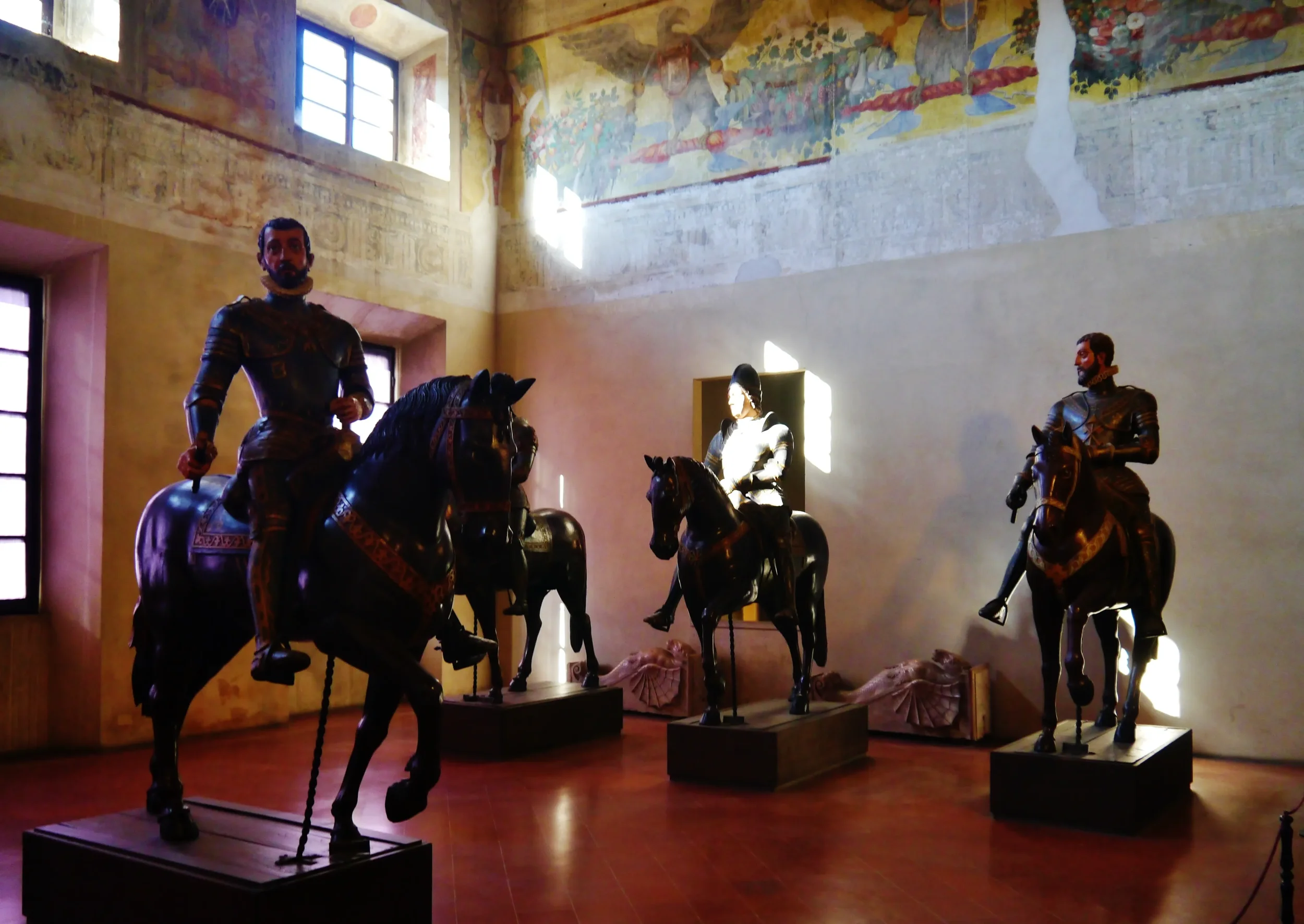 Equestrian statues displayed beneath frescoed walls in Palazzo Ducale, Sabbioneta.