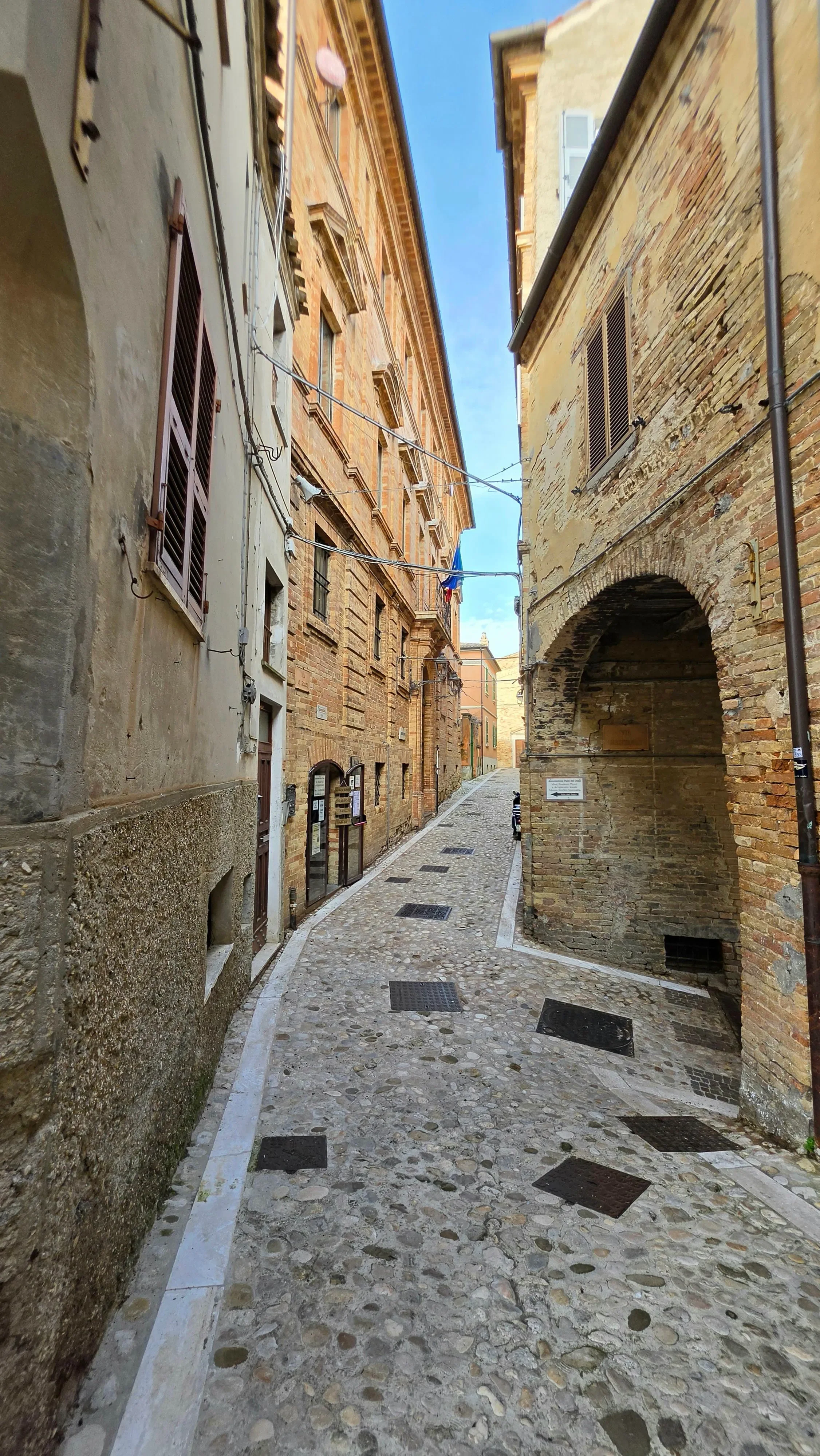 A narrow cobbled lane between historic brick buildings, with an arched passage on the right