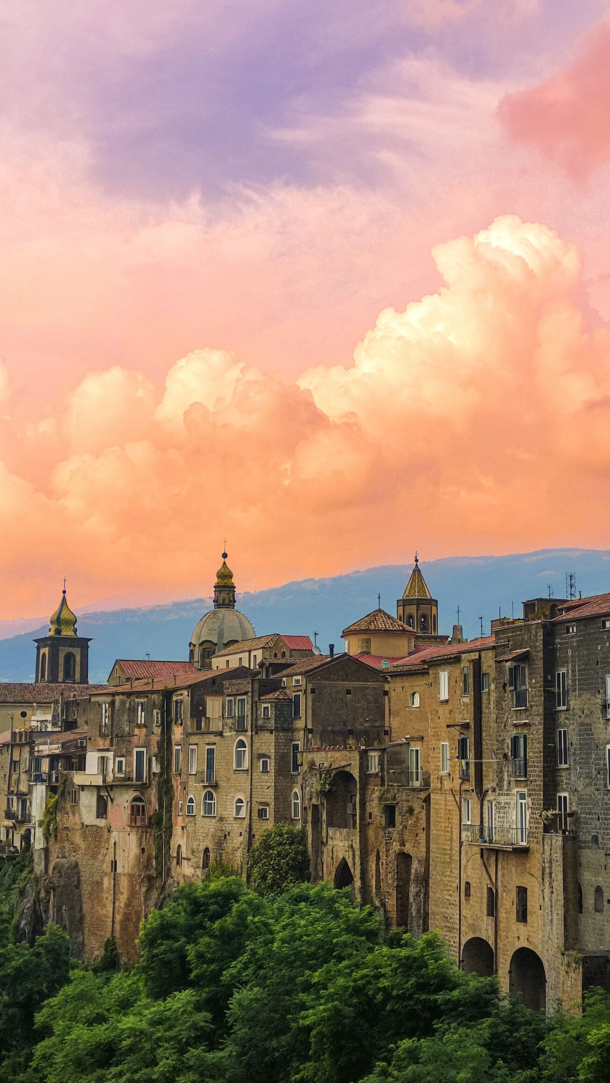 Sant’Agata de’ Goti’s cliffside old town and church domes beneath a pink and orange evening sky.