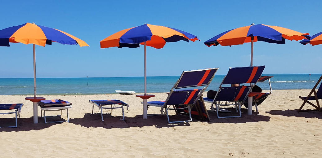 Blue and orange parasols and deckchairs on a sandy beach beside the Adriatic Sea