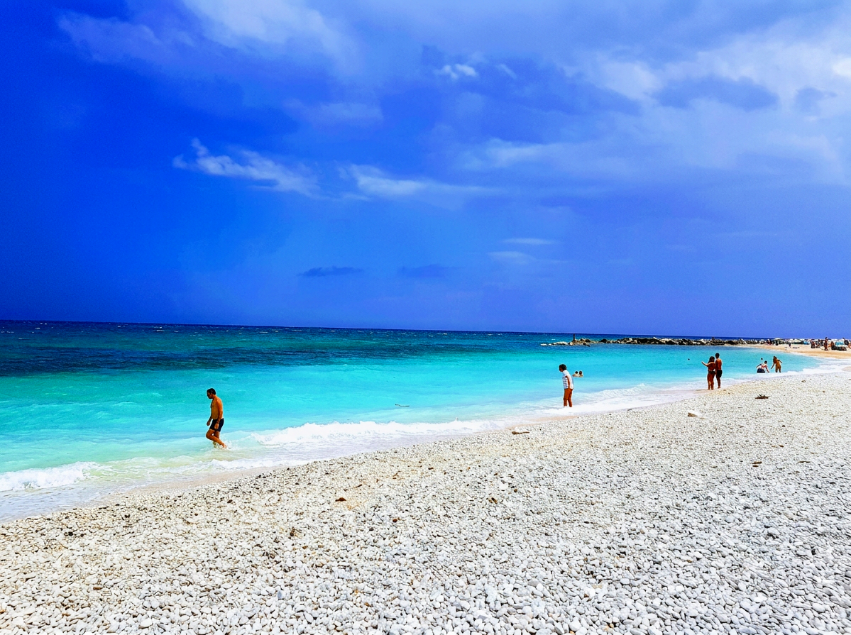 Bright turquoise water and pale pebble shoreline at San Michele Beach near Sirolo, Le Marche, Italy