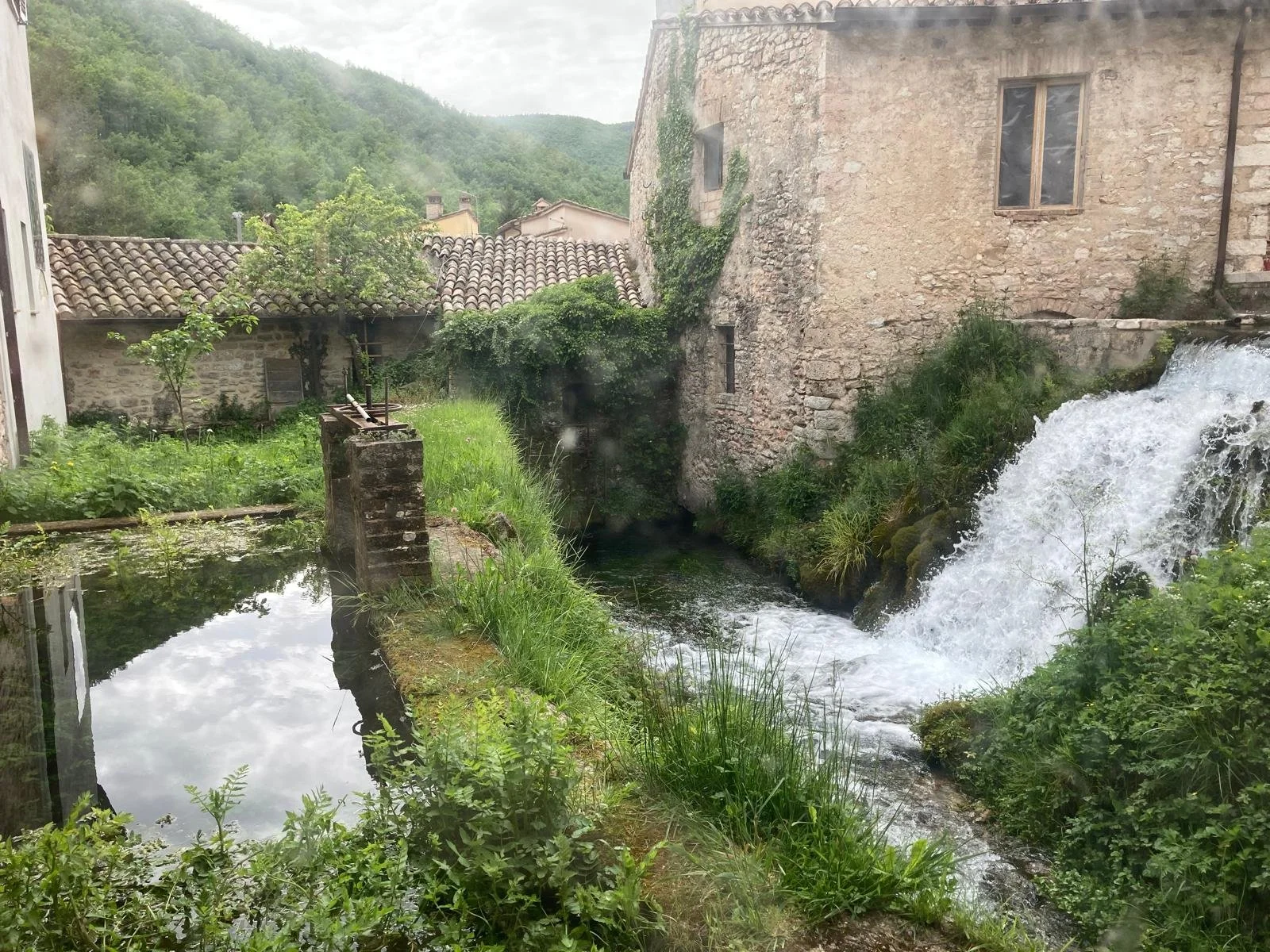 Water spilling through stone-lined channels beside old houses in Rasiglia
