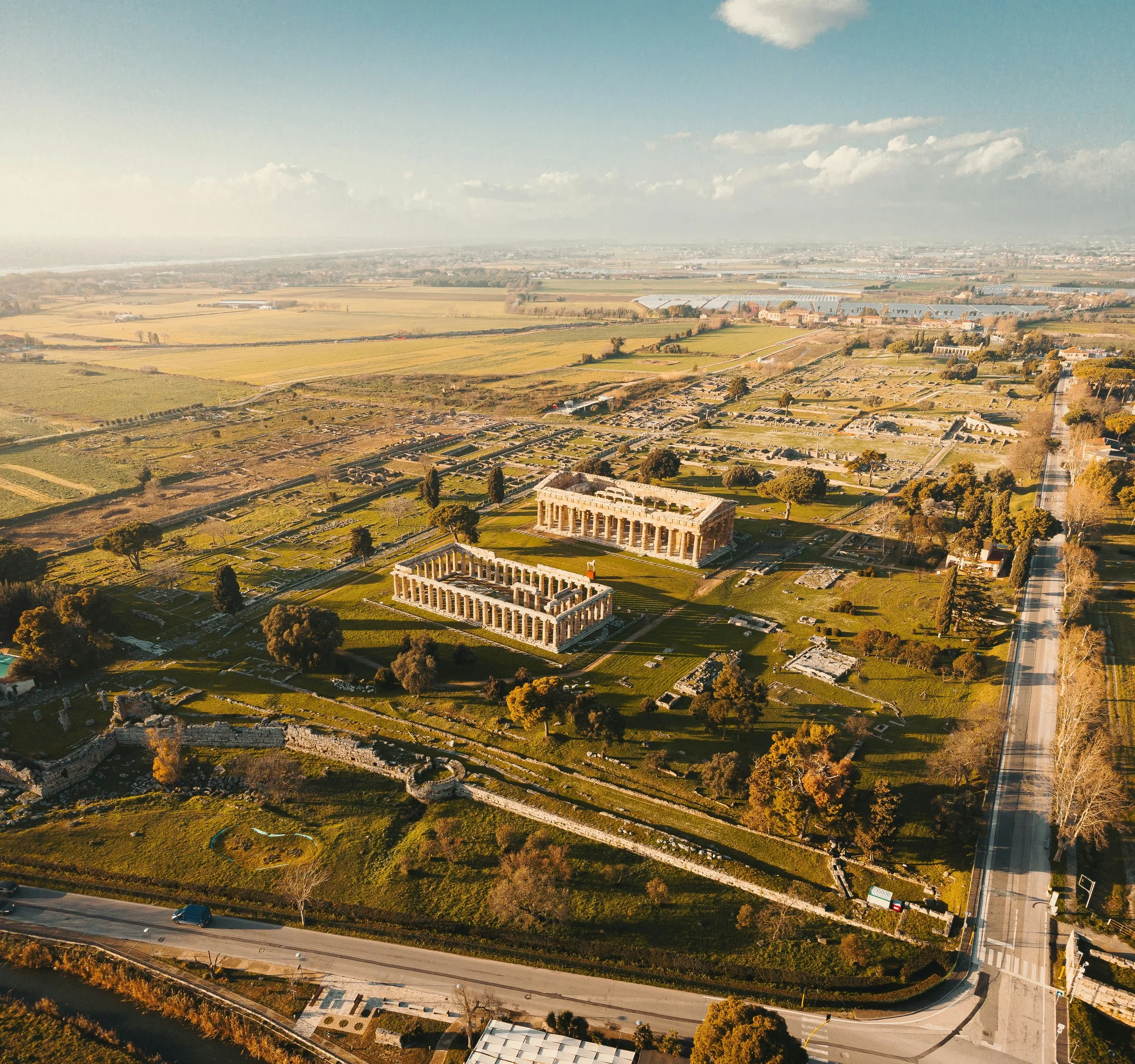 Aerial view of Paestum’s Greek temples and ancient city ruins amid the surrounding fields.