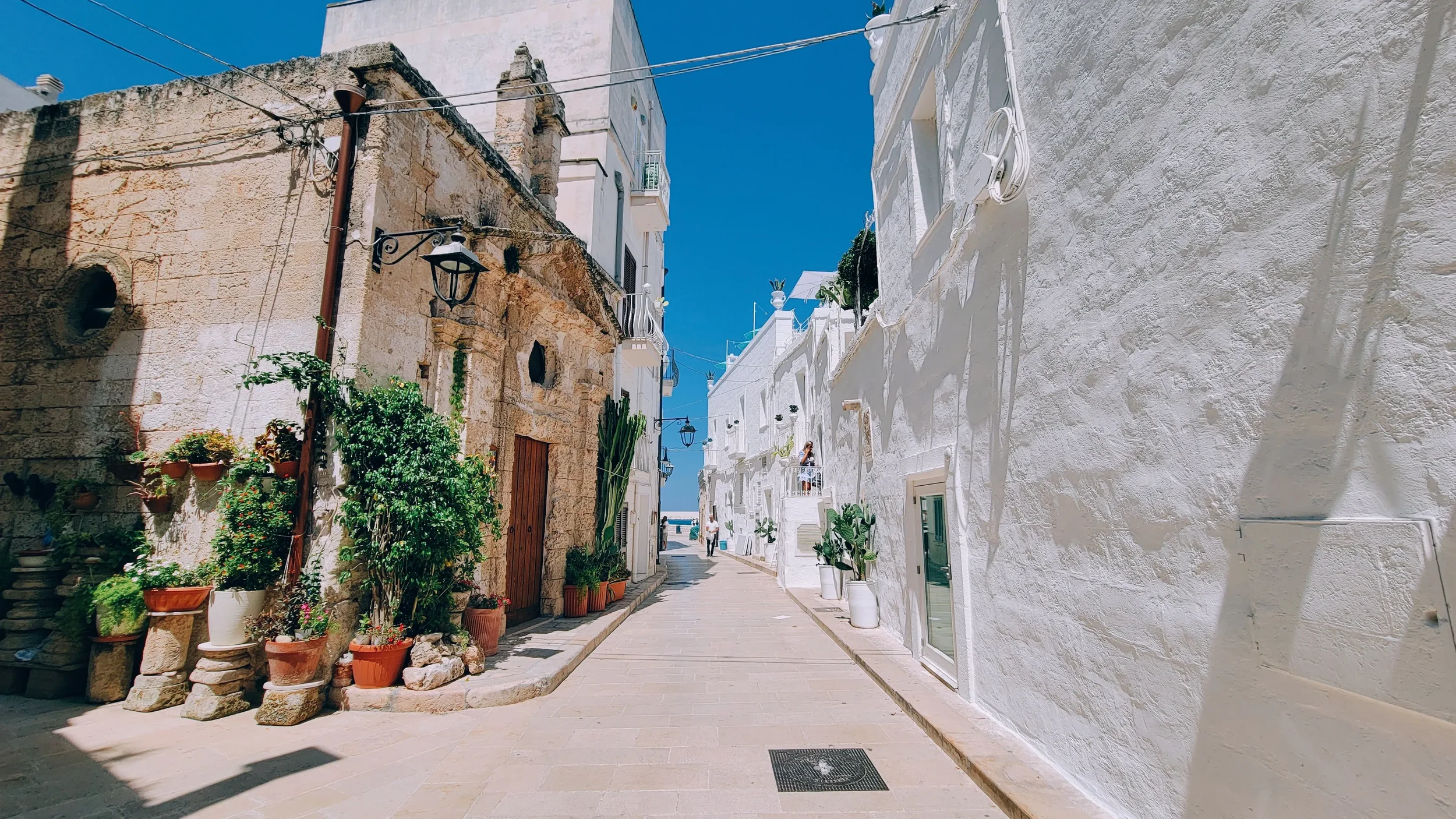 Whitewashed historic street with traditional stone houses and potted plants in Puglia, southern Italy