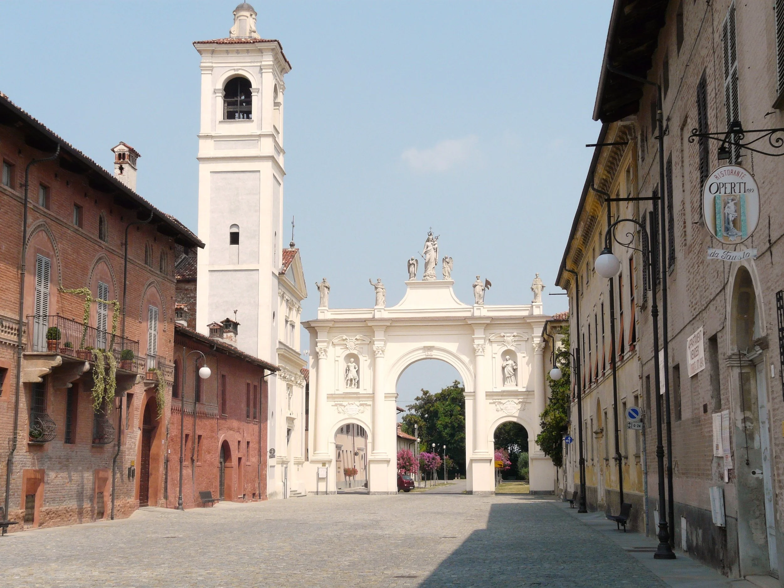 View along a cobbled street in Cherasco towards Arco del Belvedere and the adjoining bell tower.