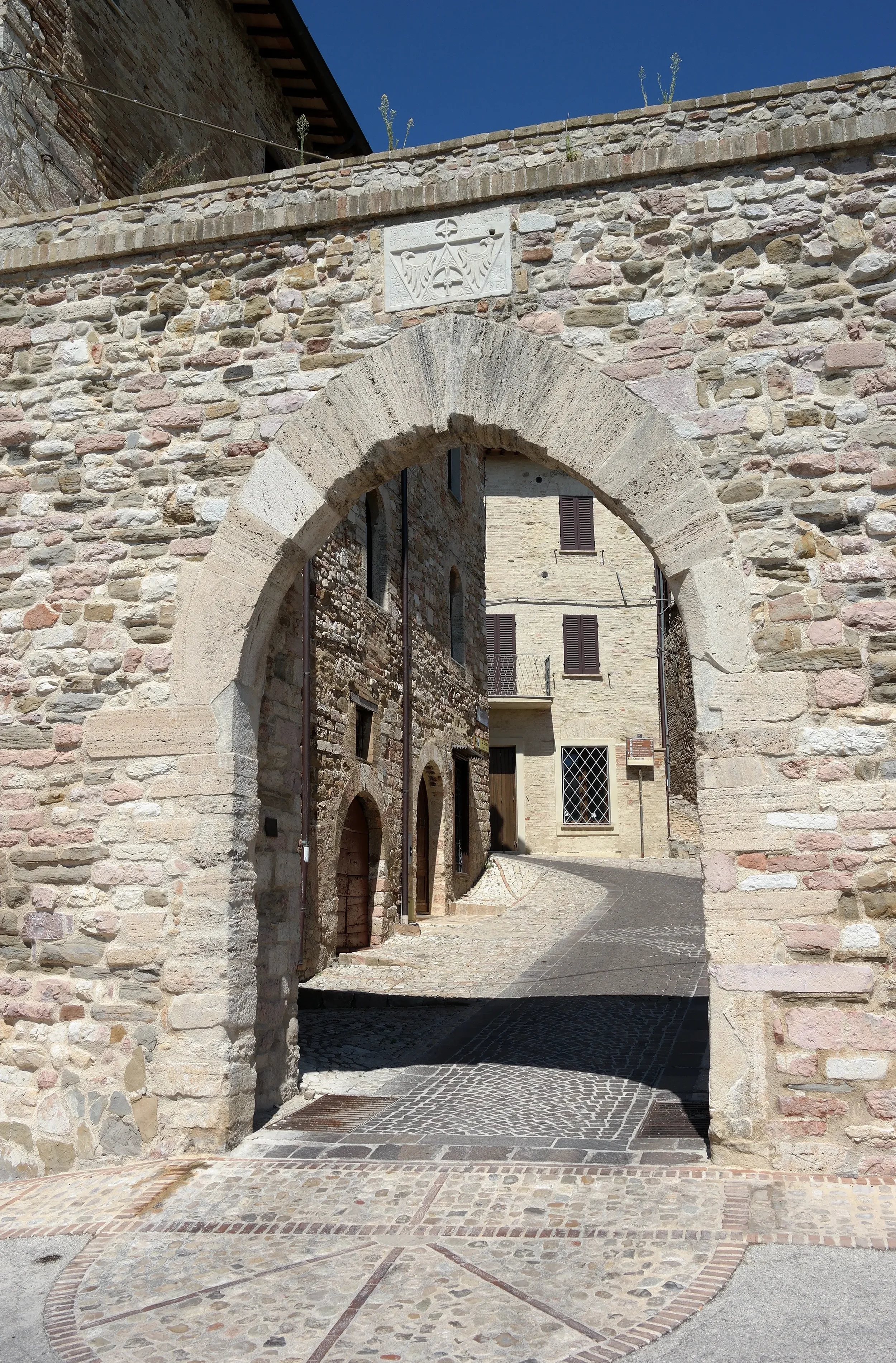 Stone arch of Porta Federico II opening onto a cobbled lane in Montefalco