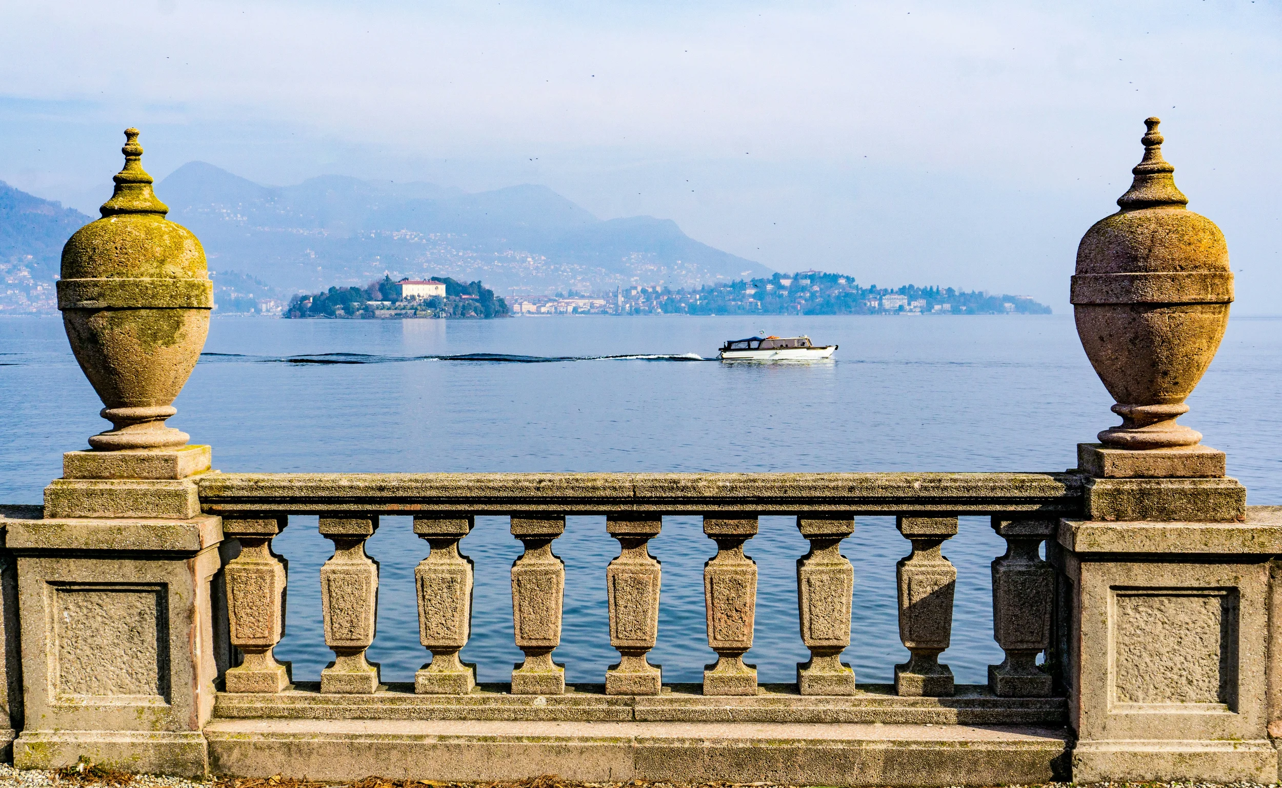 View across Lake Maggiore from Stresa in Piemonte, framed by a stone balustrade and ornamental urns