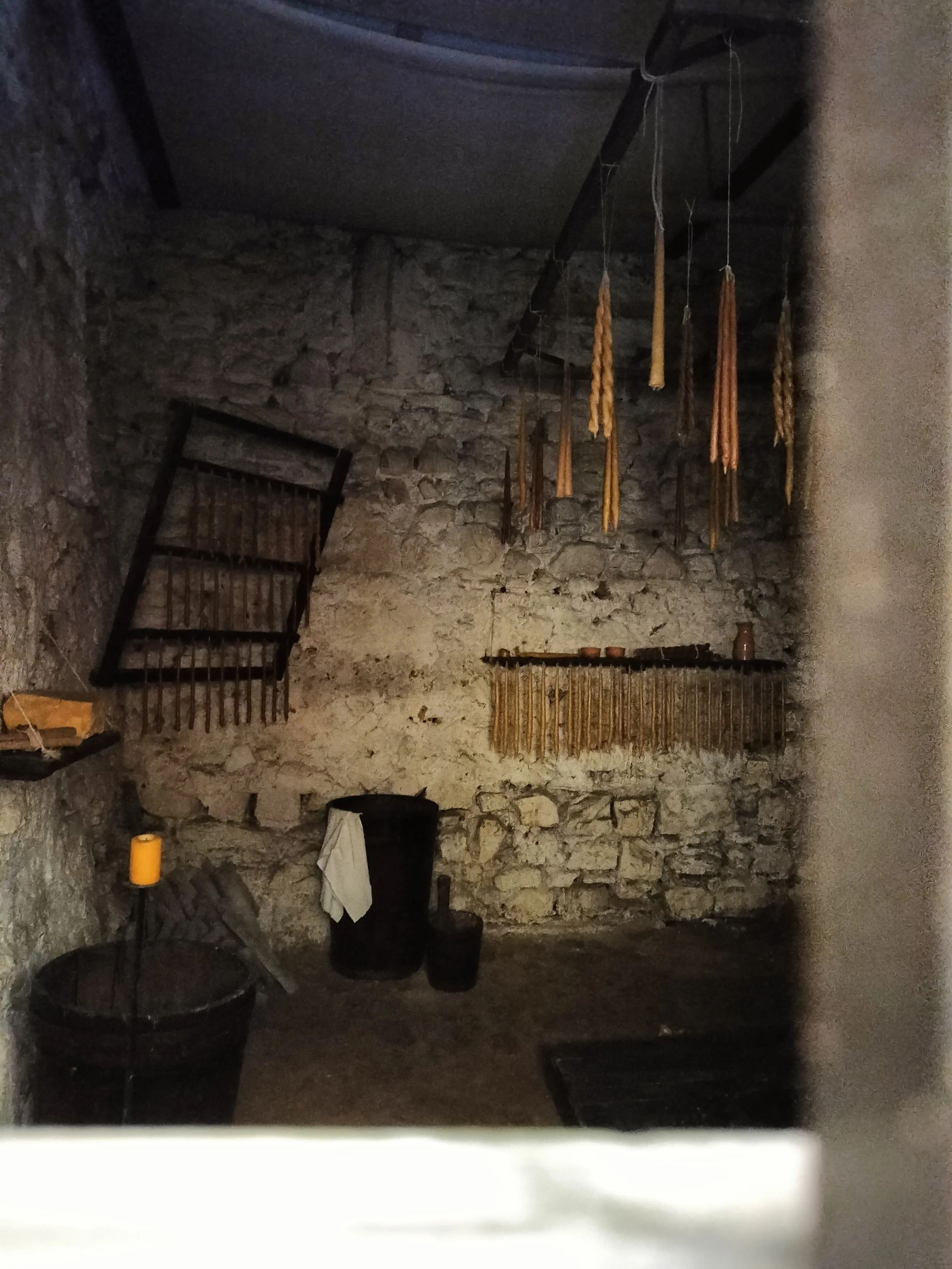 Historical display with hanging ropes and wooden implements in a stone-walled interior in Narni