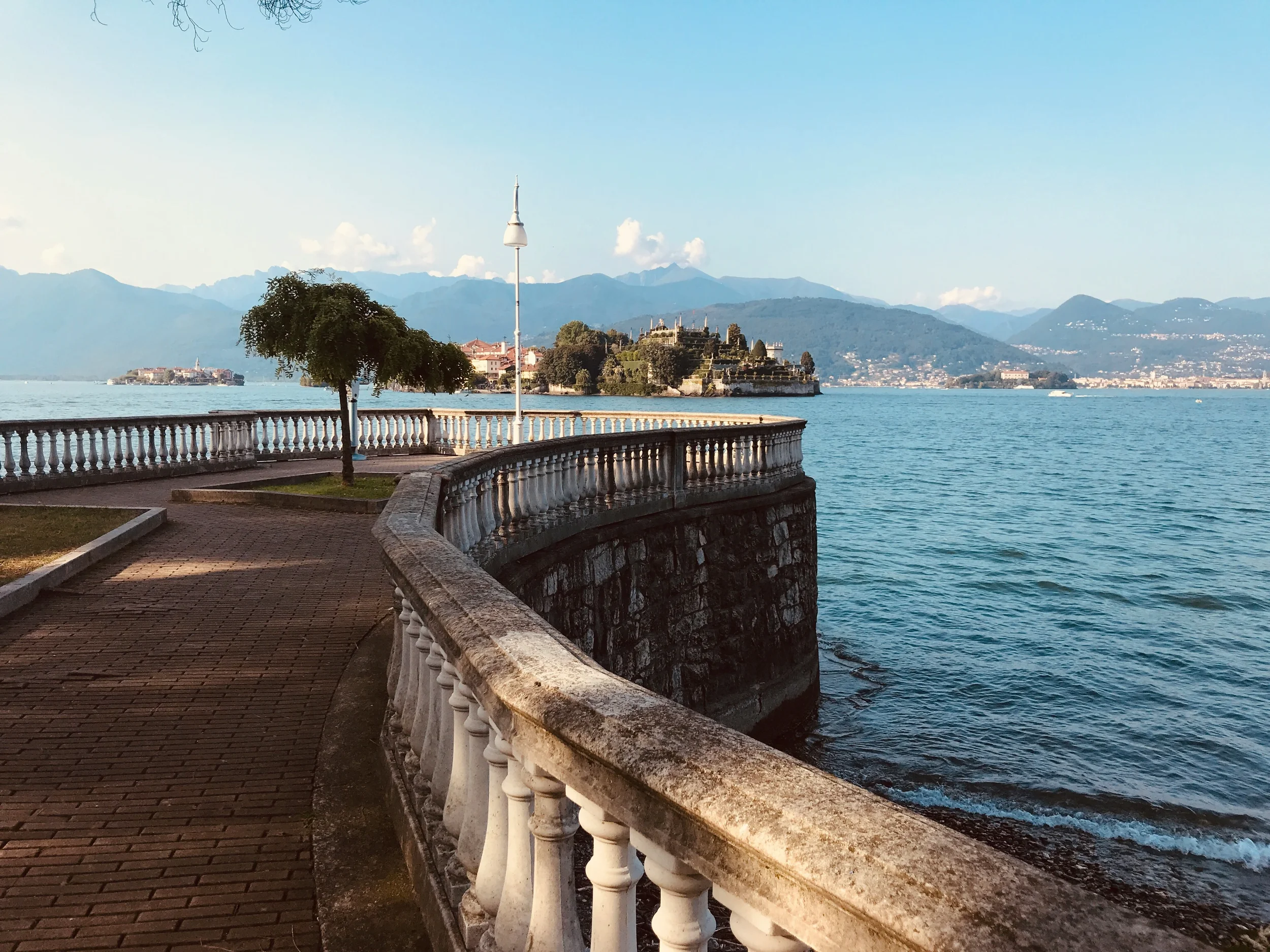 Lakeside promenade in Stresa overlooking Lake Maggiore and the Borromean Islands, with mountains in the distance.