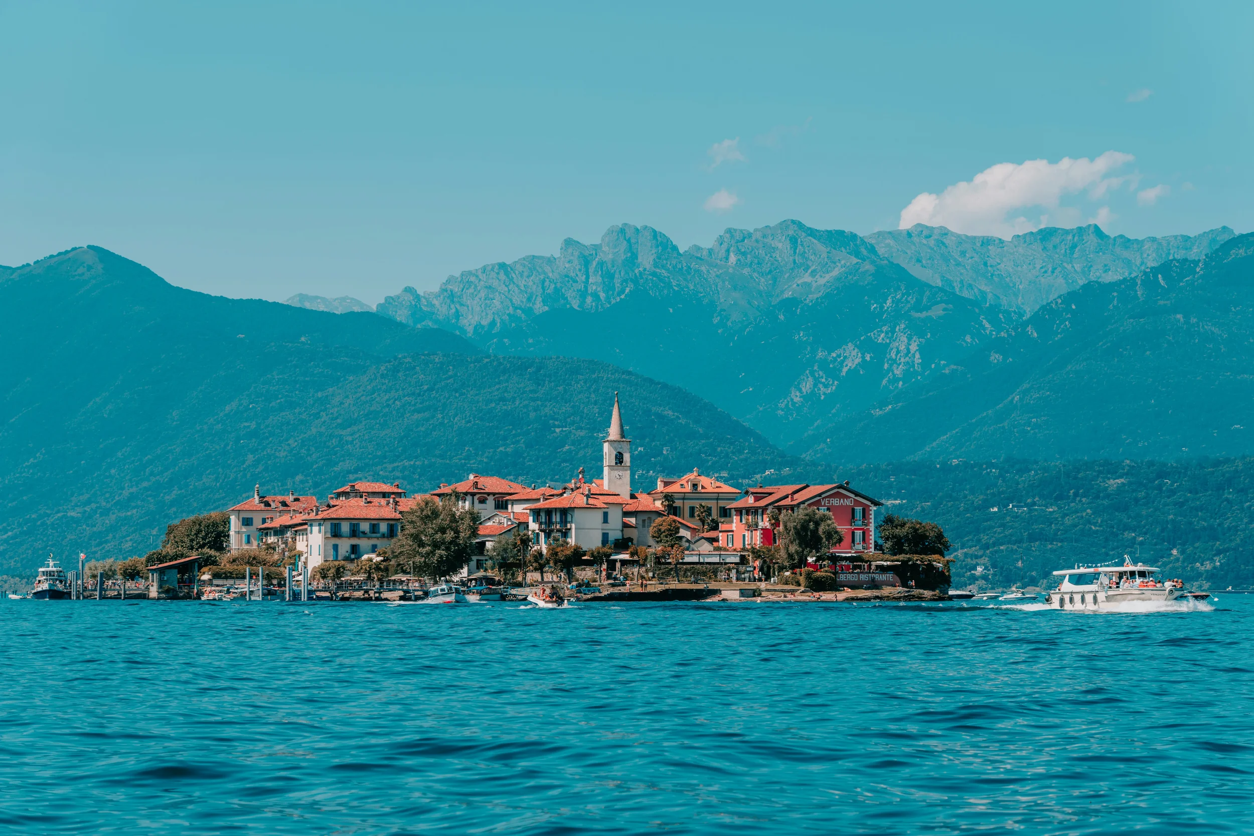 Isola dei Pescatori on Lake Maggiore, with colourful waterfront houses, boats and mountains in Piemonte, Italy.