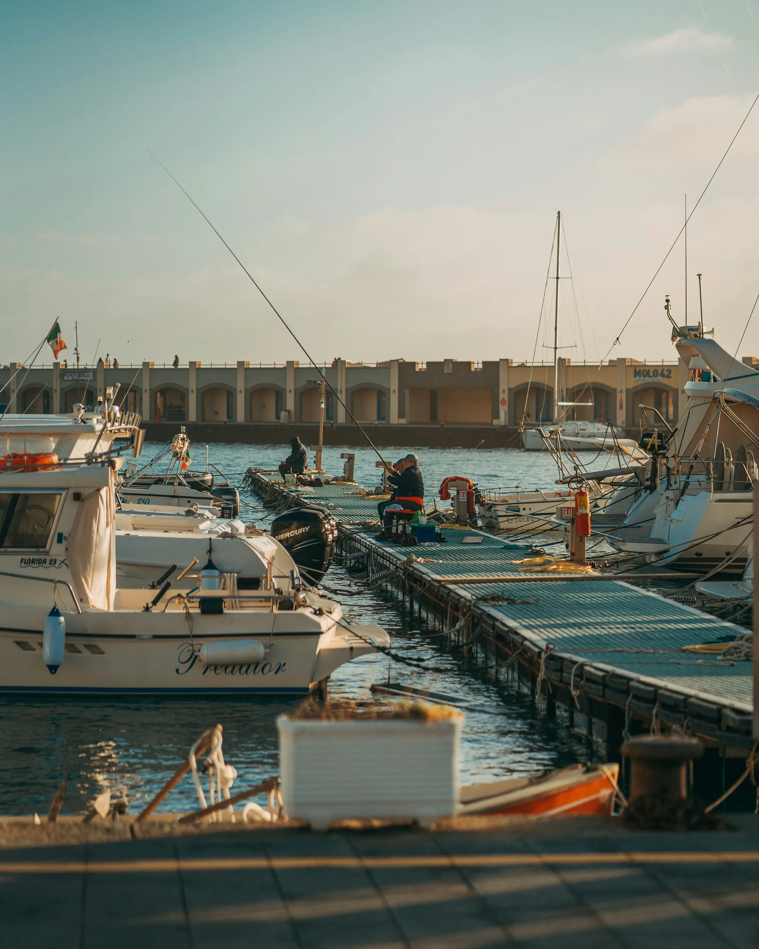 Small fishing boats moored alongside floating pontoons in Acciaroli harbour.