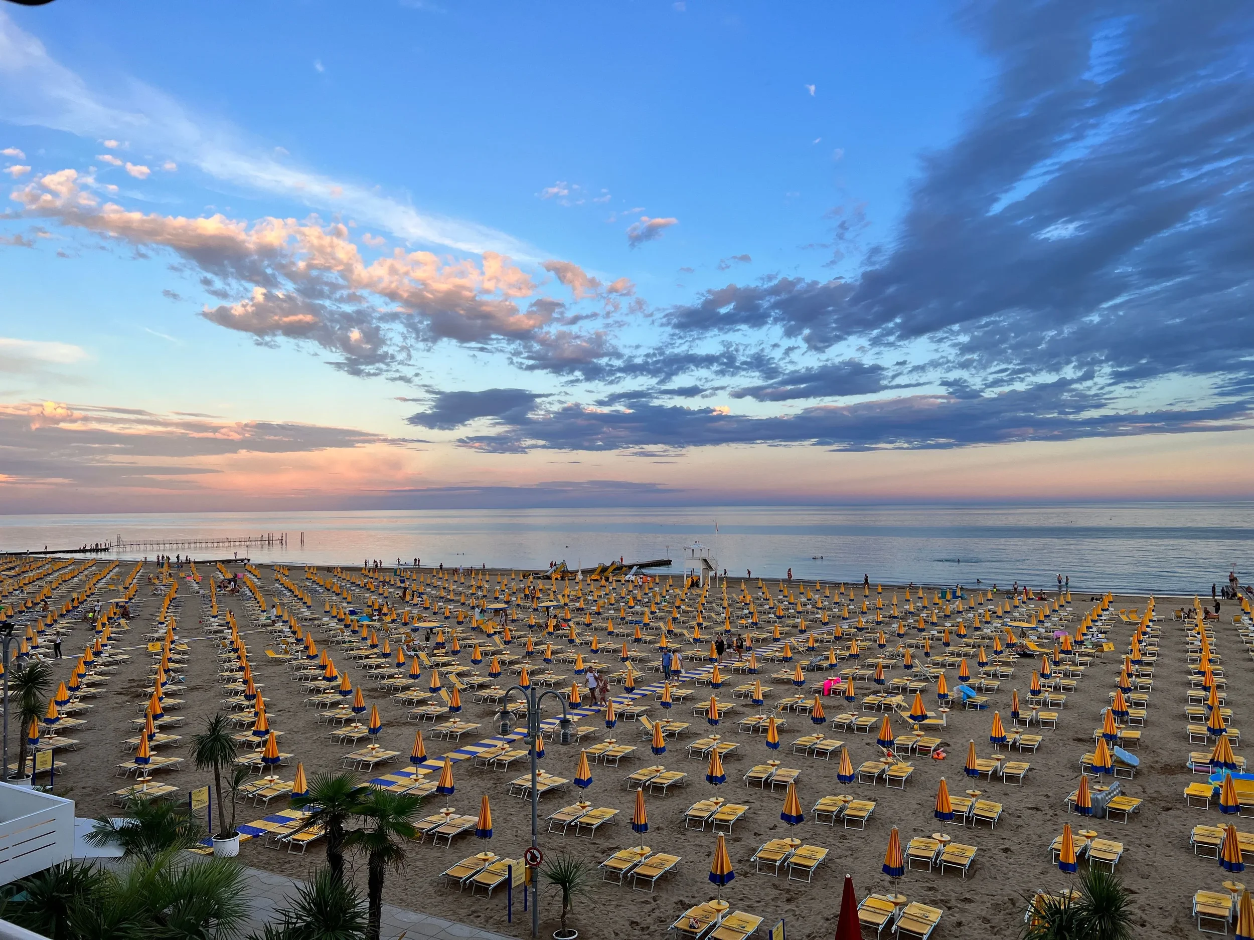 Rows of colourful beach umbrellas on Riccione beach at sunset