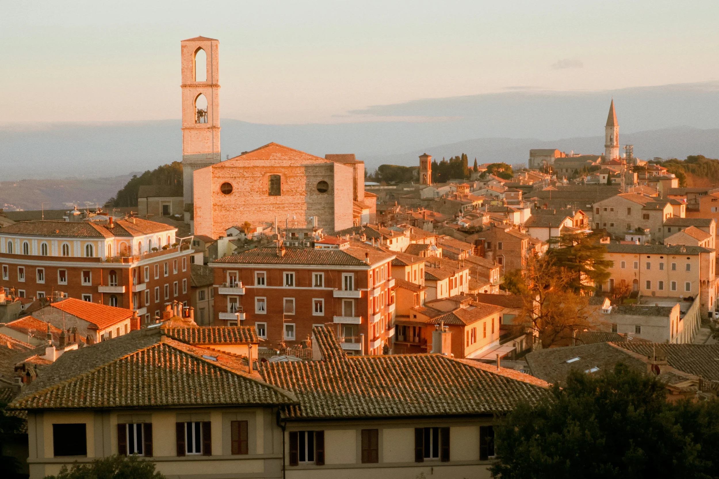Golden-hour view over Perugia’s terracotta rooftops, with the bell towers of San Domenico and San Pietro, Umbria.