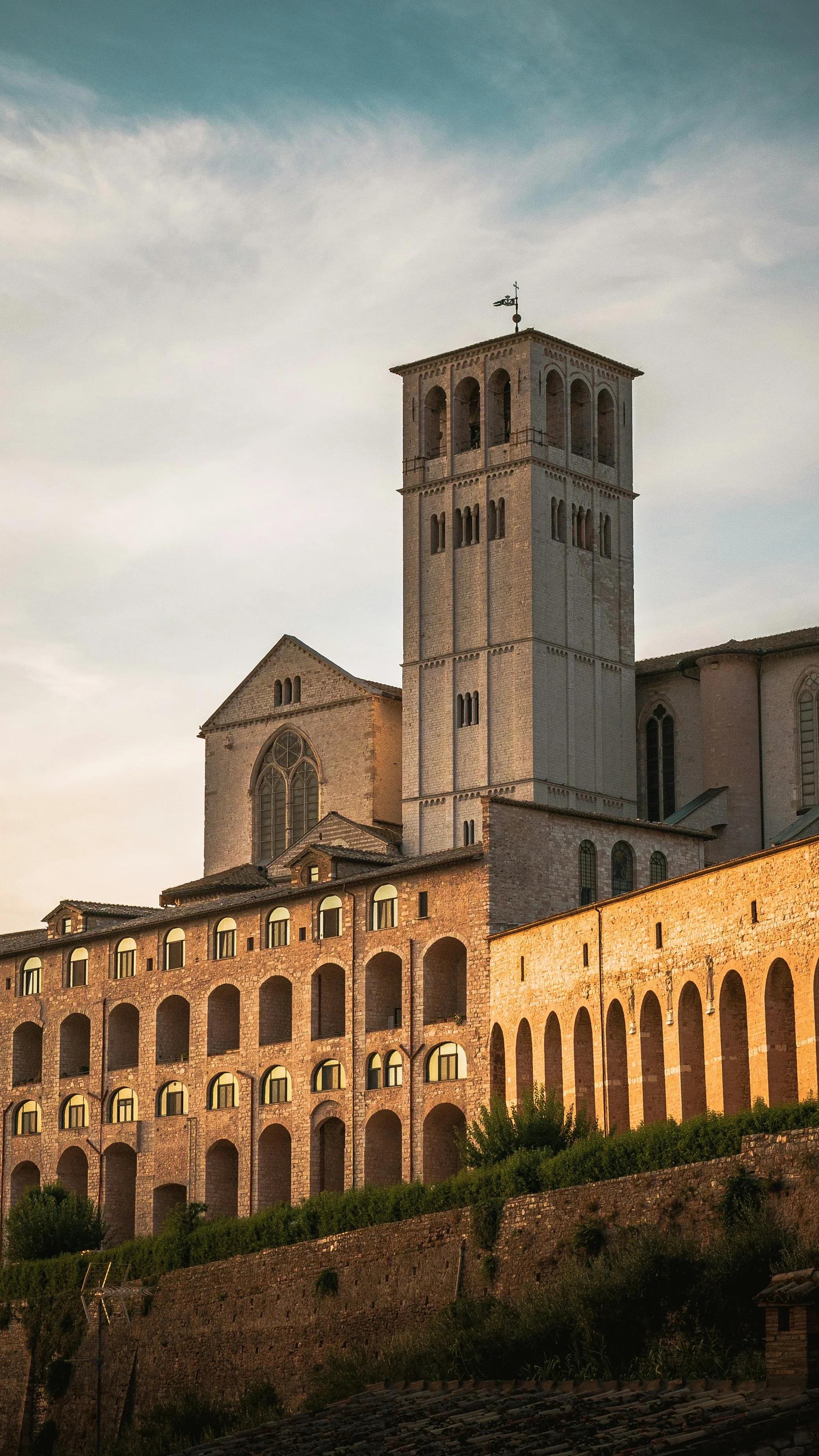 Basilica of Saint Francis and the arcaded walls of the Sacro Convento in warm light, Assisi