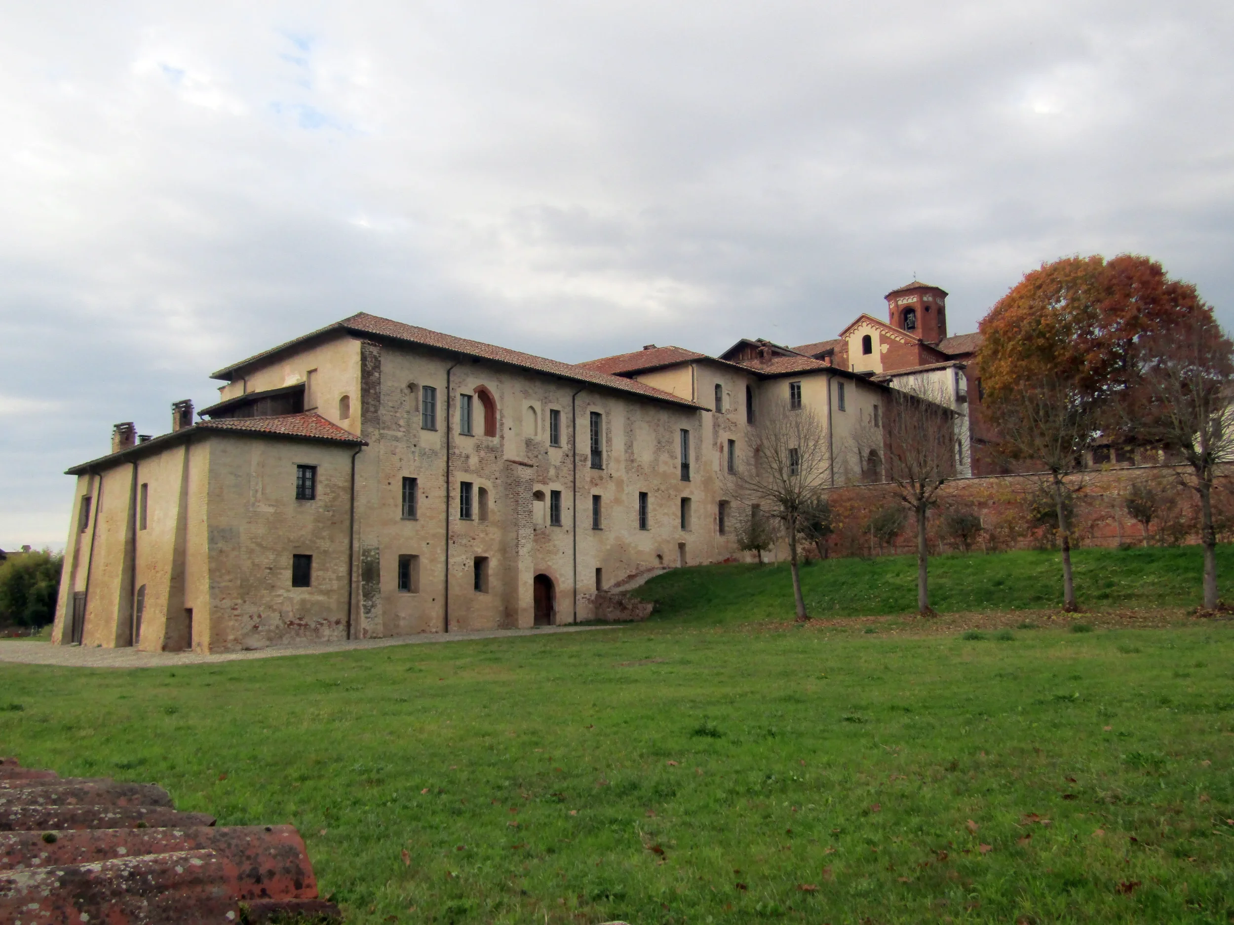 Morimondo monastery buildings seen across a green lawn beneath an autumn sky.