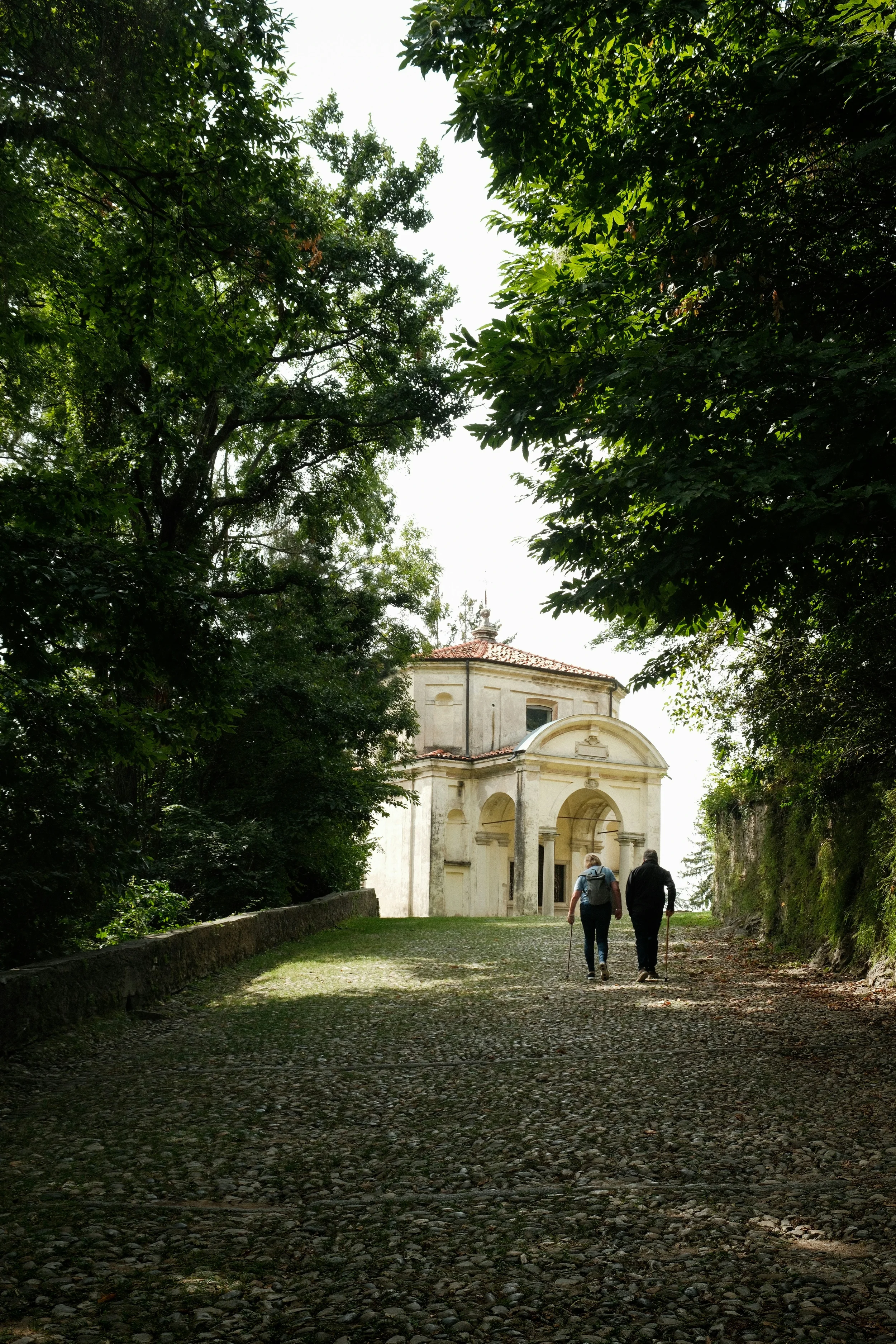 Walkers on a cobbled path beside a chapel at Sacro Monte di Varese, Lombardy