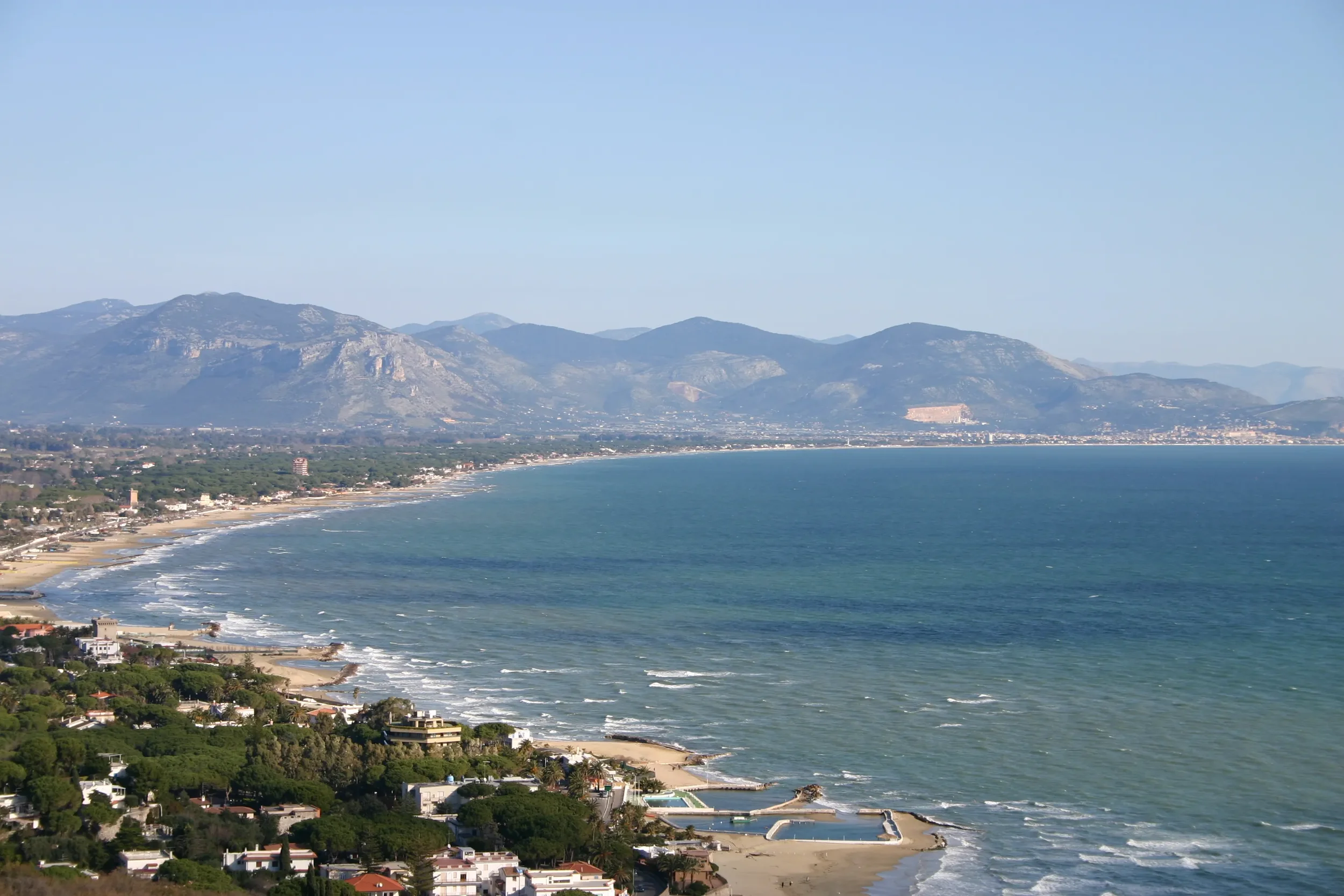 The coastline below San Felice Circeo, with a curving beach and mountains across the bay.