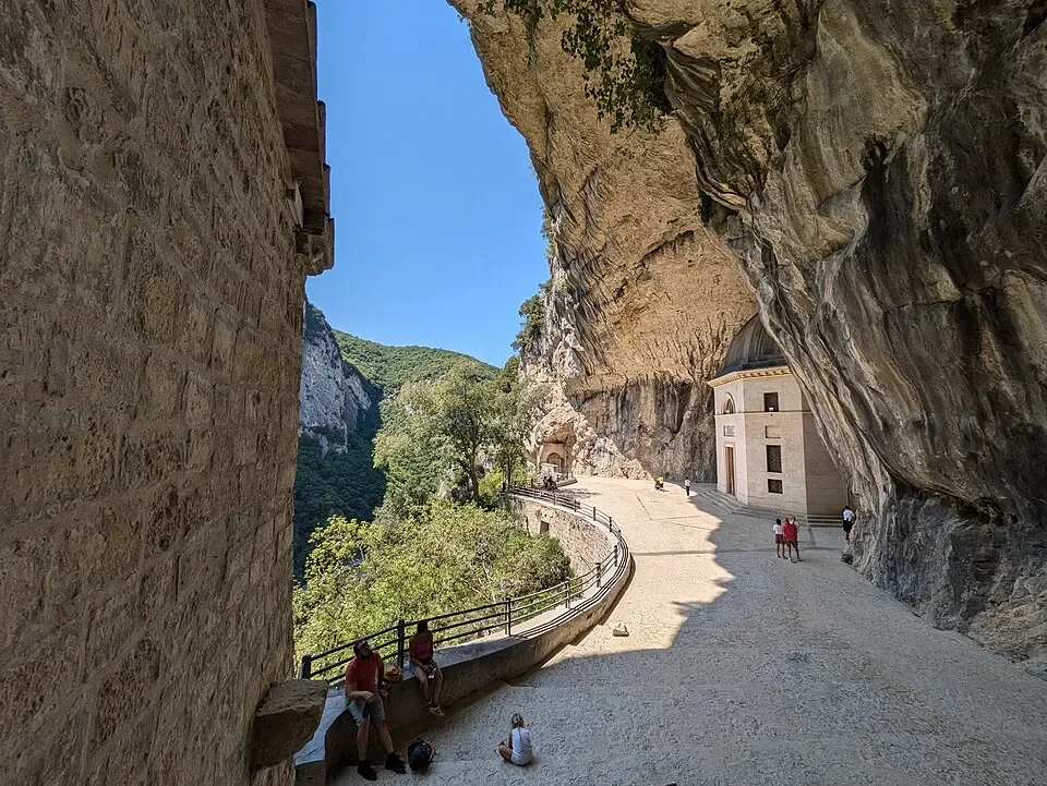 The curving walkway beside the Tempio del Valadier, framed by limestone cliffs and the cave entrance
