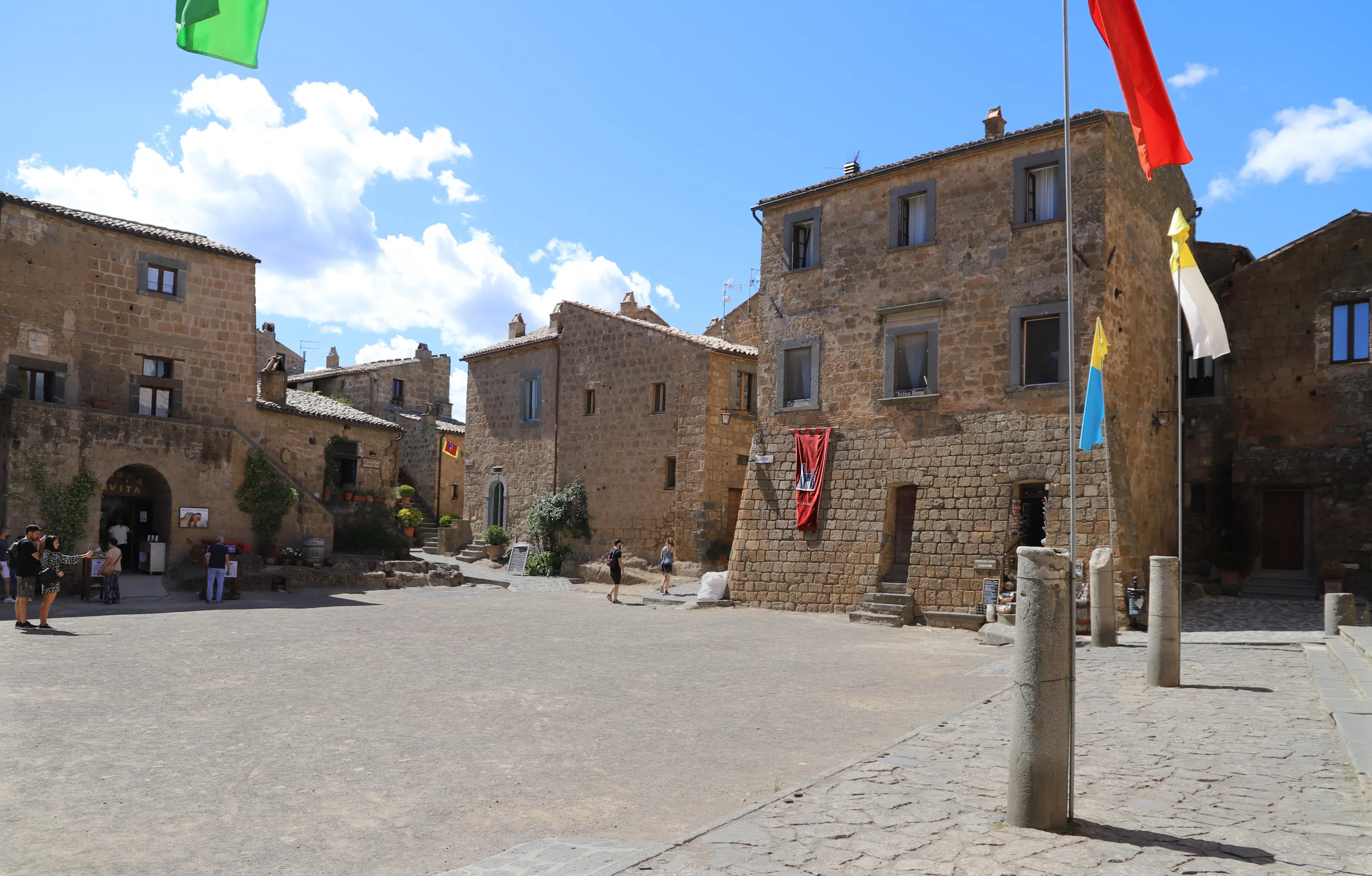 Historic stone buildings and flags around Piazza San Donato in Civita di Bagnoregio.