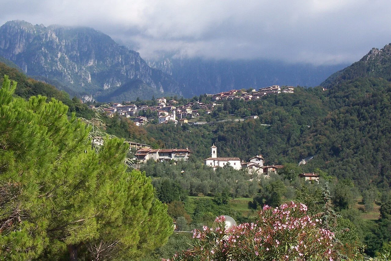 Villa and Vesio among green slopes beneath cloud-covered mountains in Tremosine.