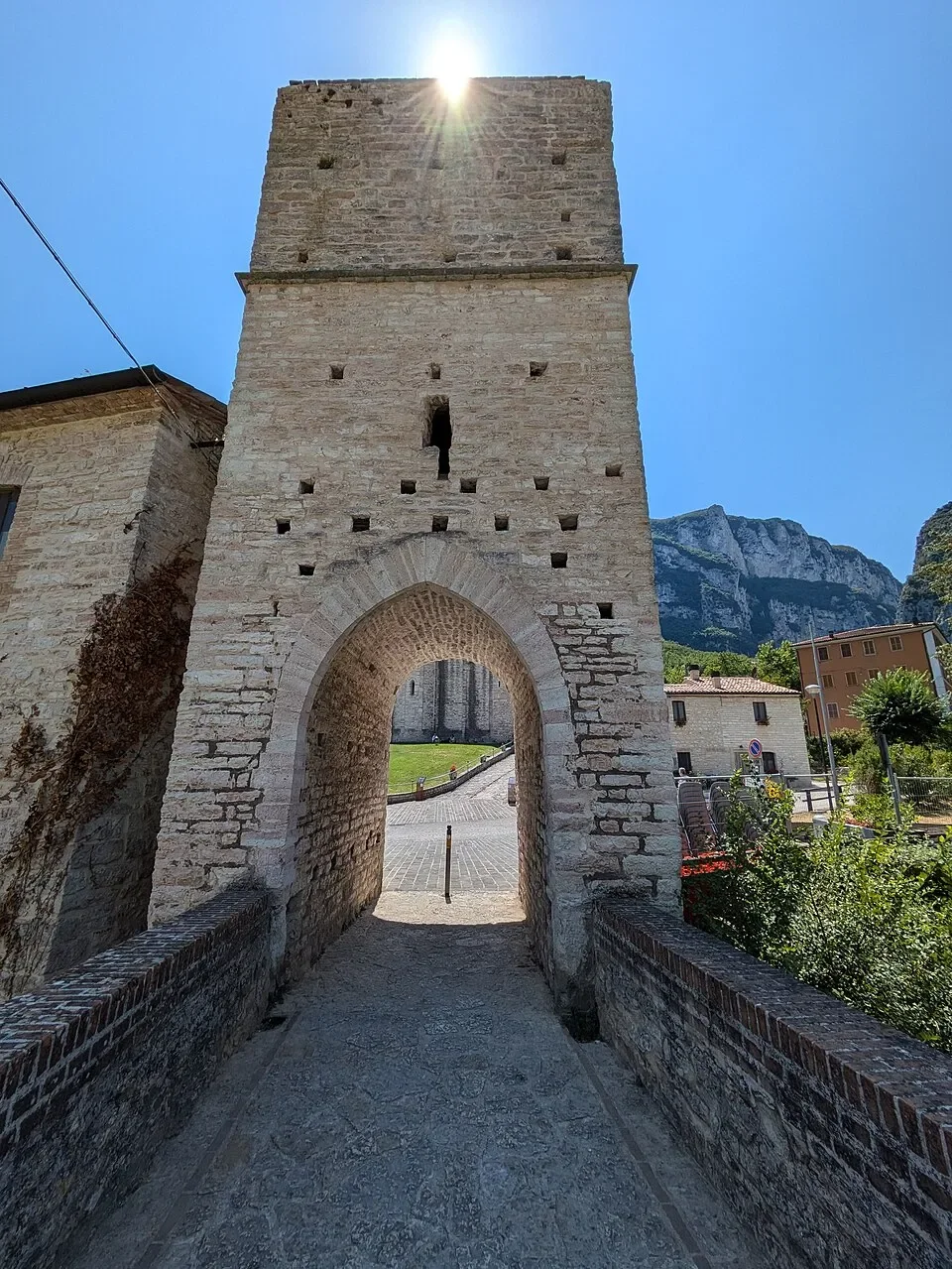 The tall stone gate tower at the end of the bridge beside San Vittore alle Chiuse