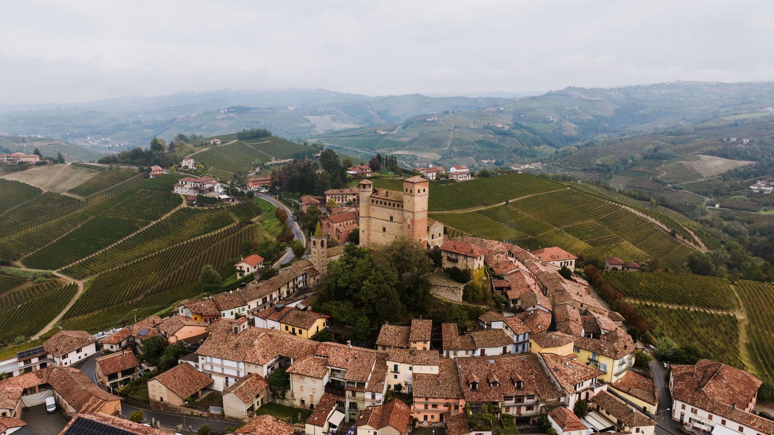 Aerial view of Serralunga d’Alba with its medieval castle, terracotta rooftops and surrounding Langhe vineyards, Piemonte.