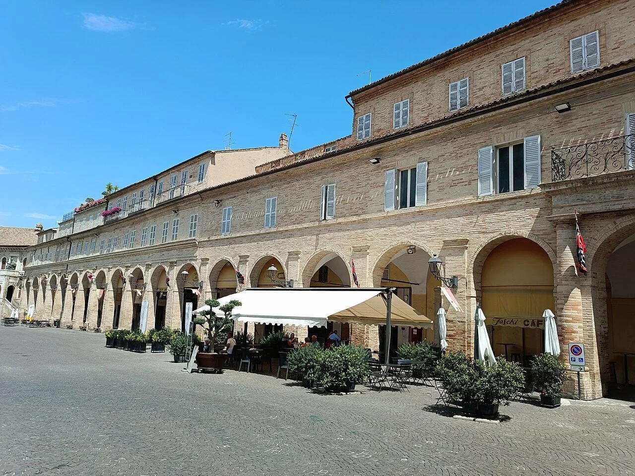 Brick arcades and café terraces lining Piazza del Popolo in Fermo, Le Marche