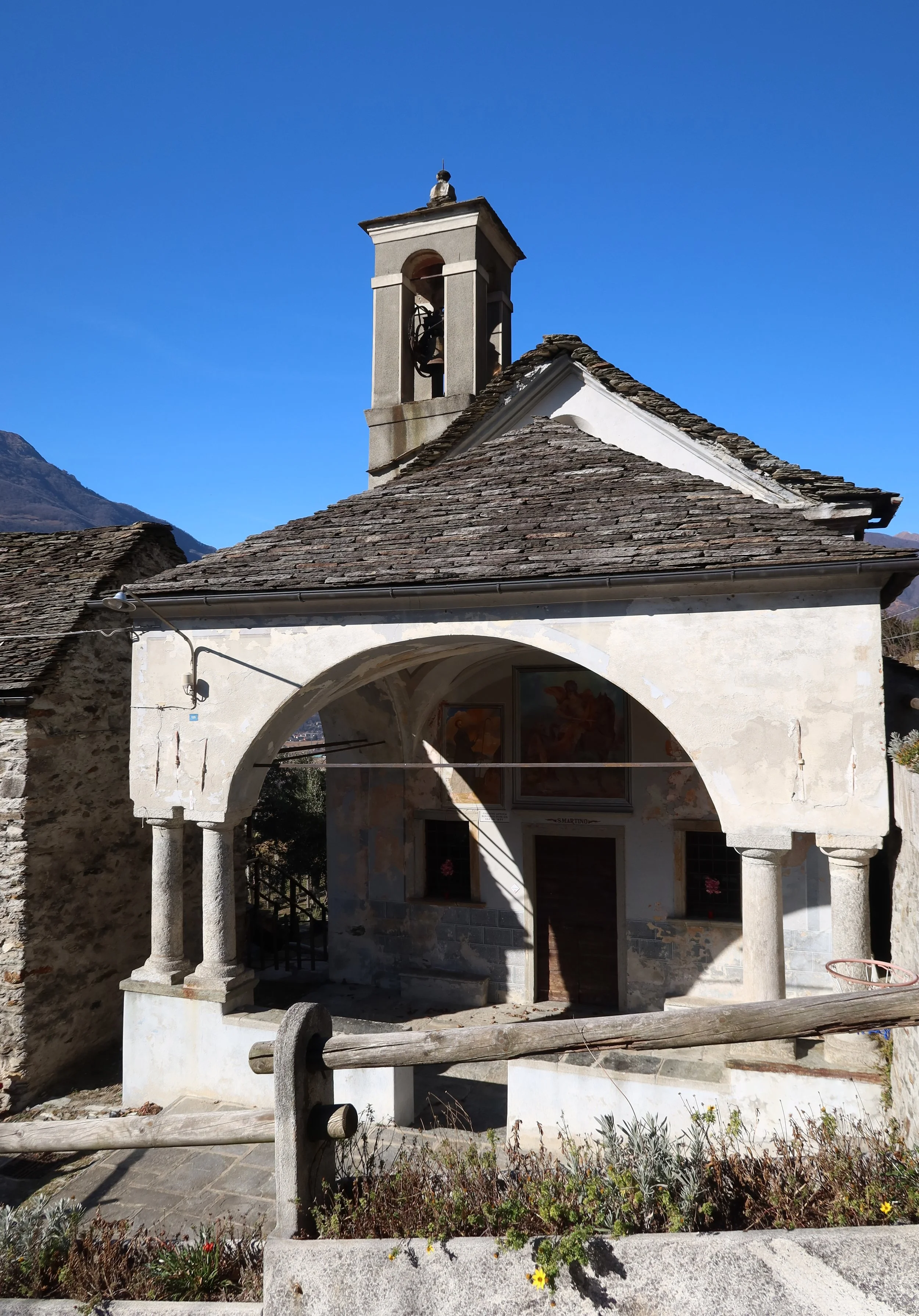 The Oratory of San Martino in Genestredo, with a stone-tiled roof, arched porch and bell tower.